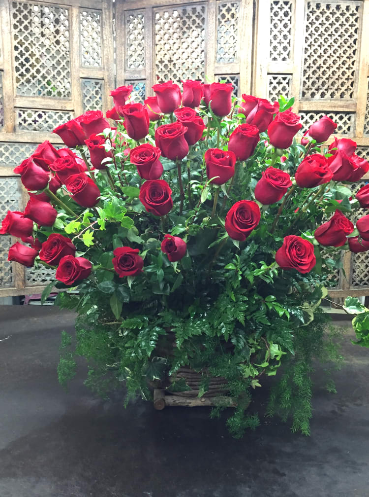 Large bouquet of red roses with greenery in a basket