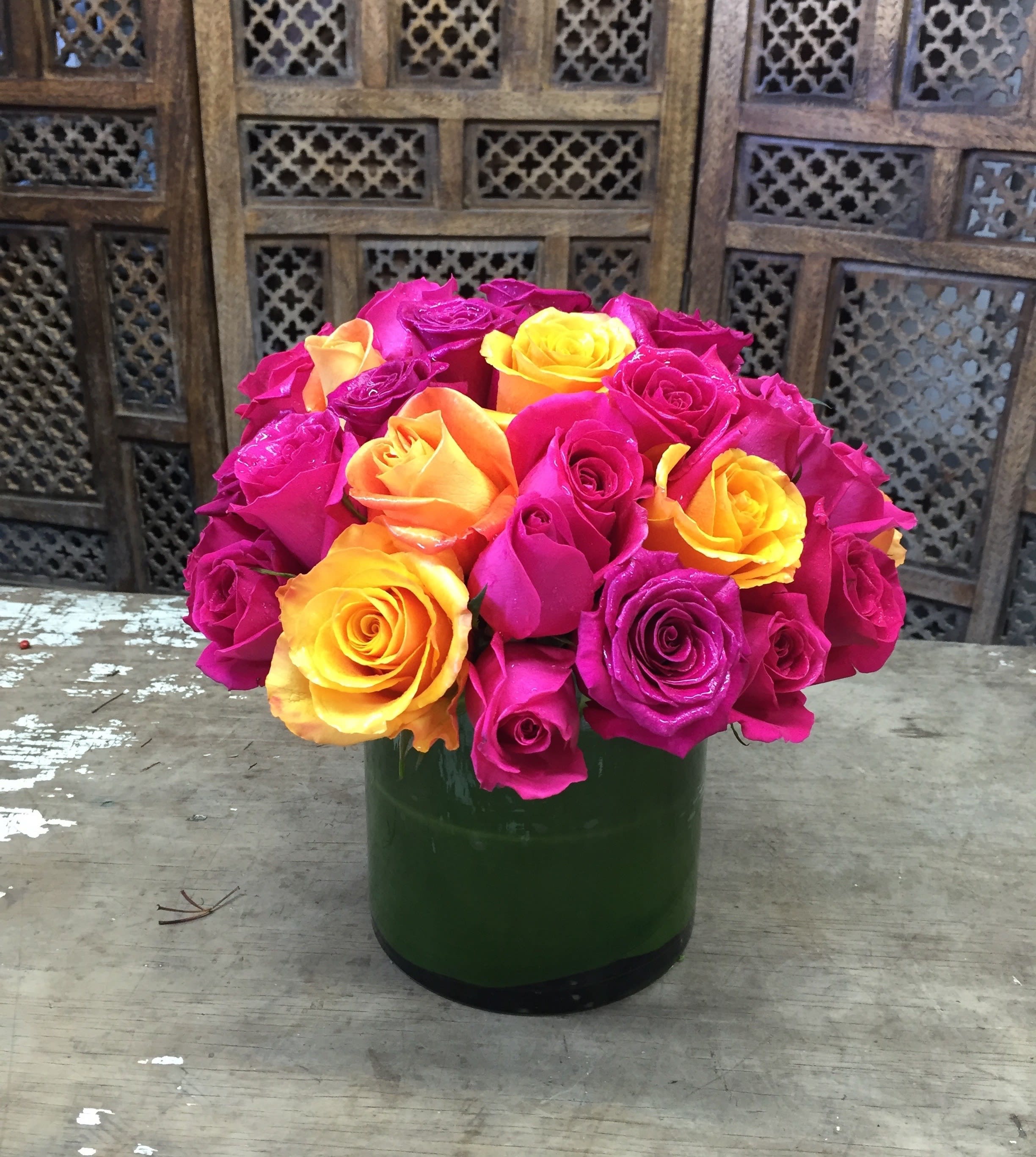 Bouquet of pink, yellow, and orange roses in a green vase