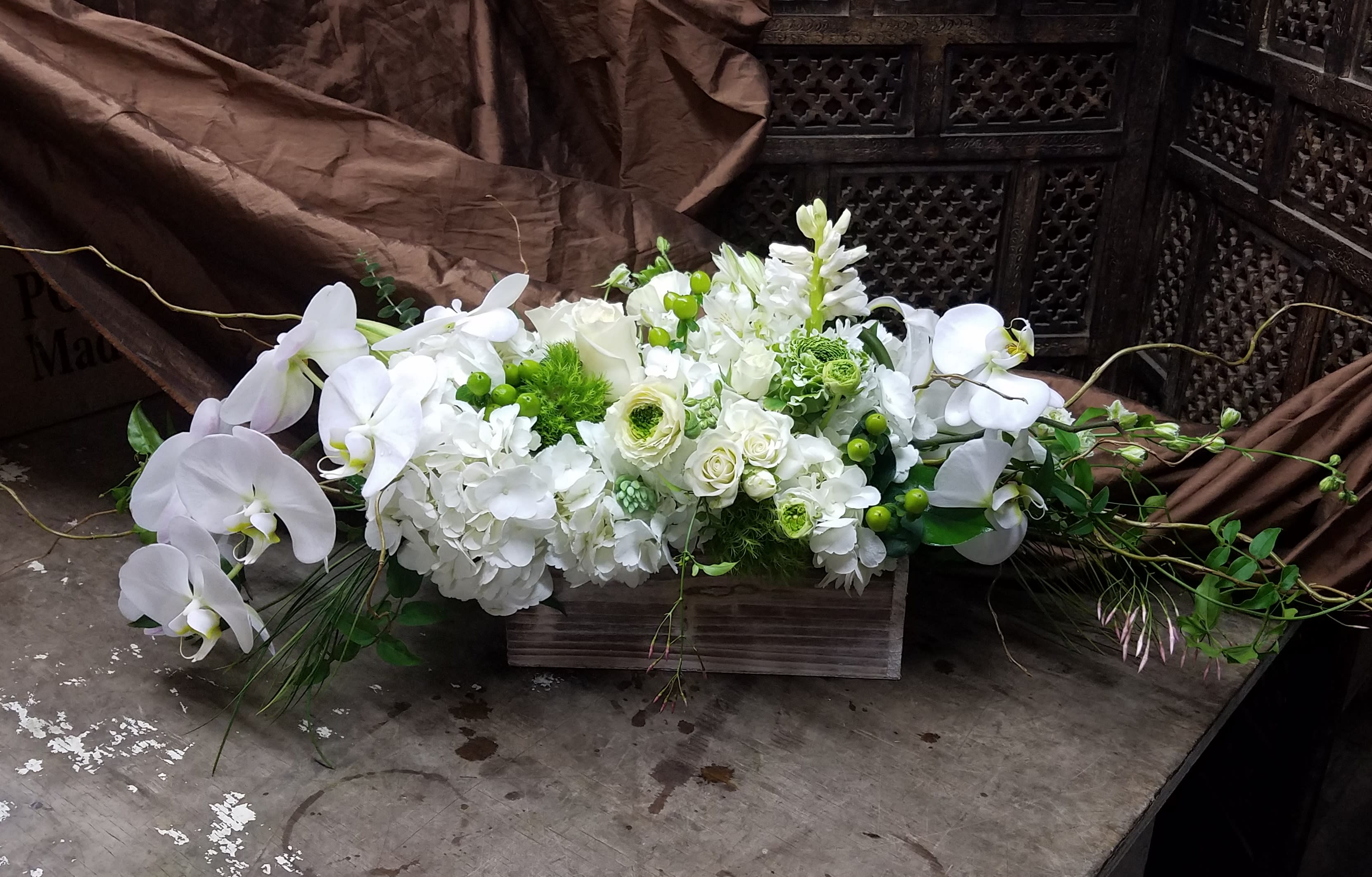 White floral arrangement with orchids and hydrangeas in a wooden box