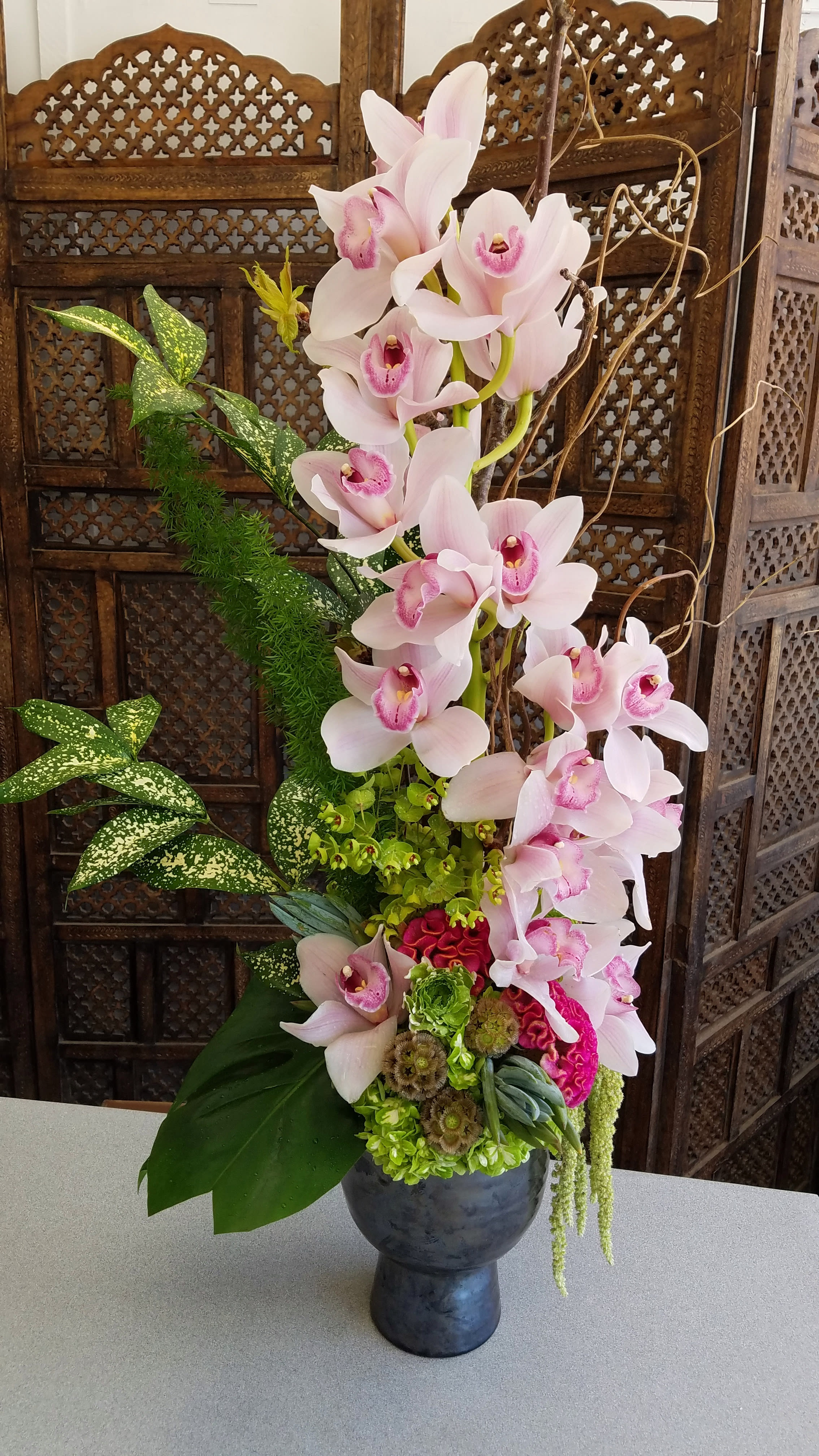 Tall arrangement of pink orchids in a dark vase