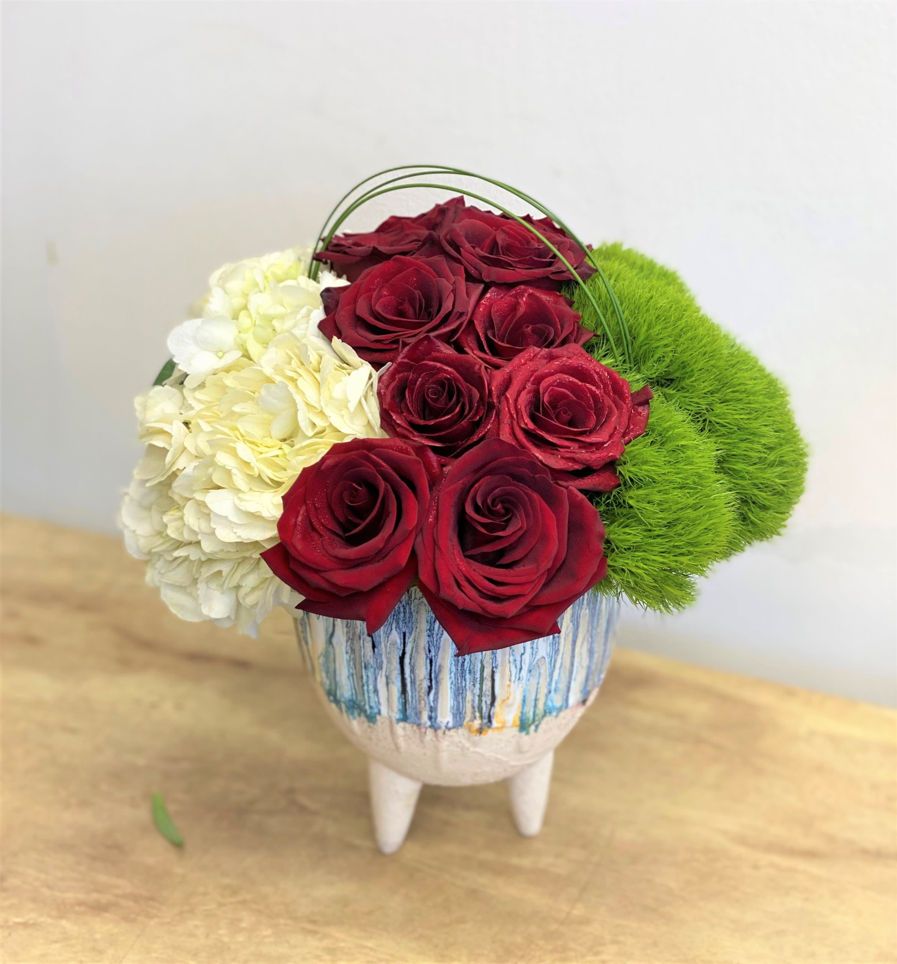 Red roses with white hydrangea and green moss in a decorative vase