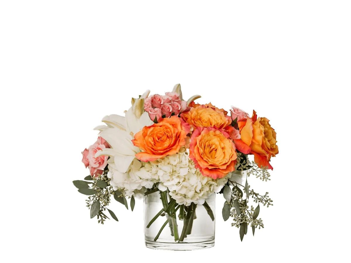 Orange and pink roses with white lilies and hydrangeas in a clear glass vase