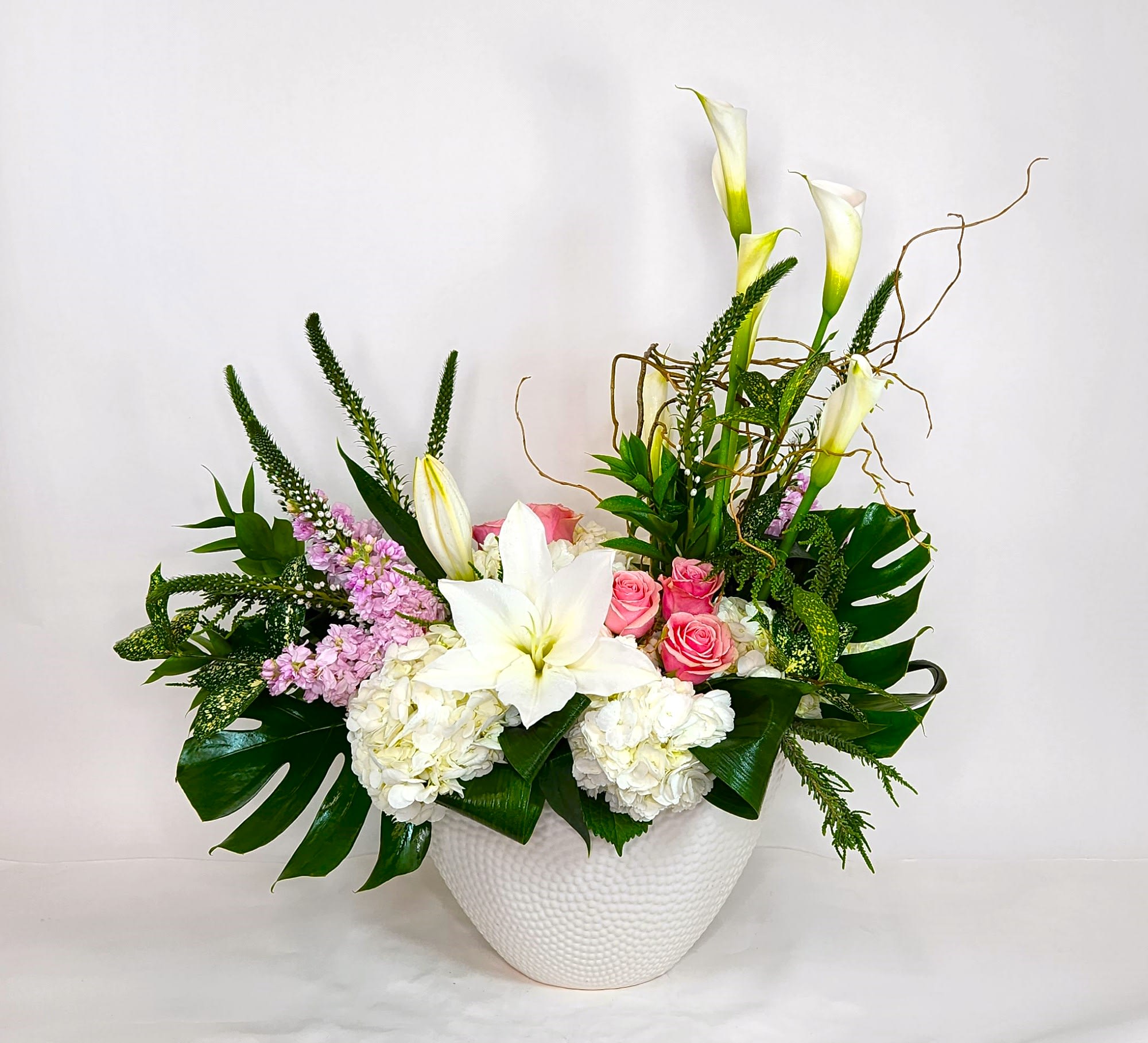 White lilies, pink roses, and hydrangeas in a white vase