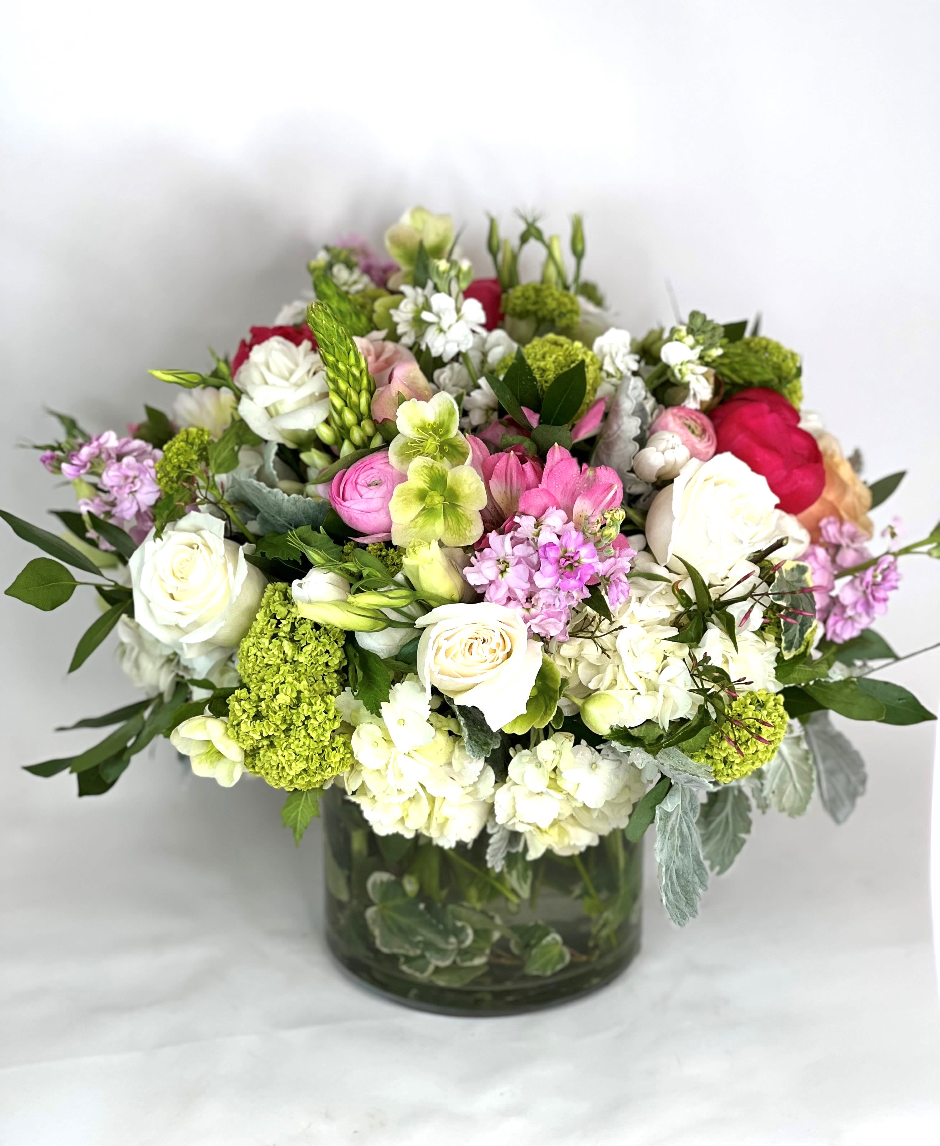Mixed bouquet of white, pink, and green flowers in a glass vase
