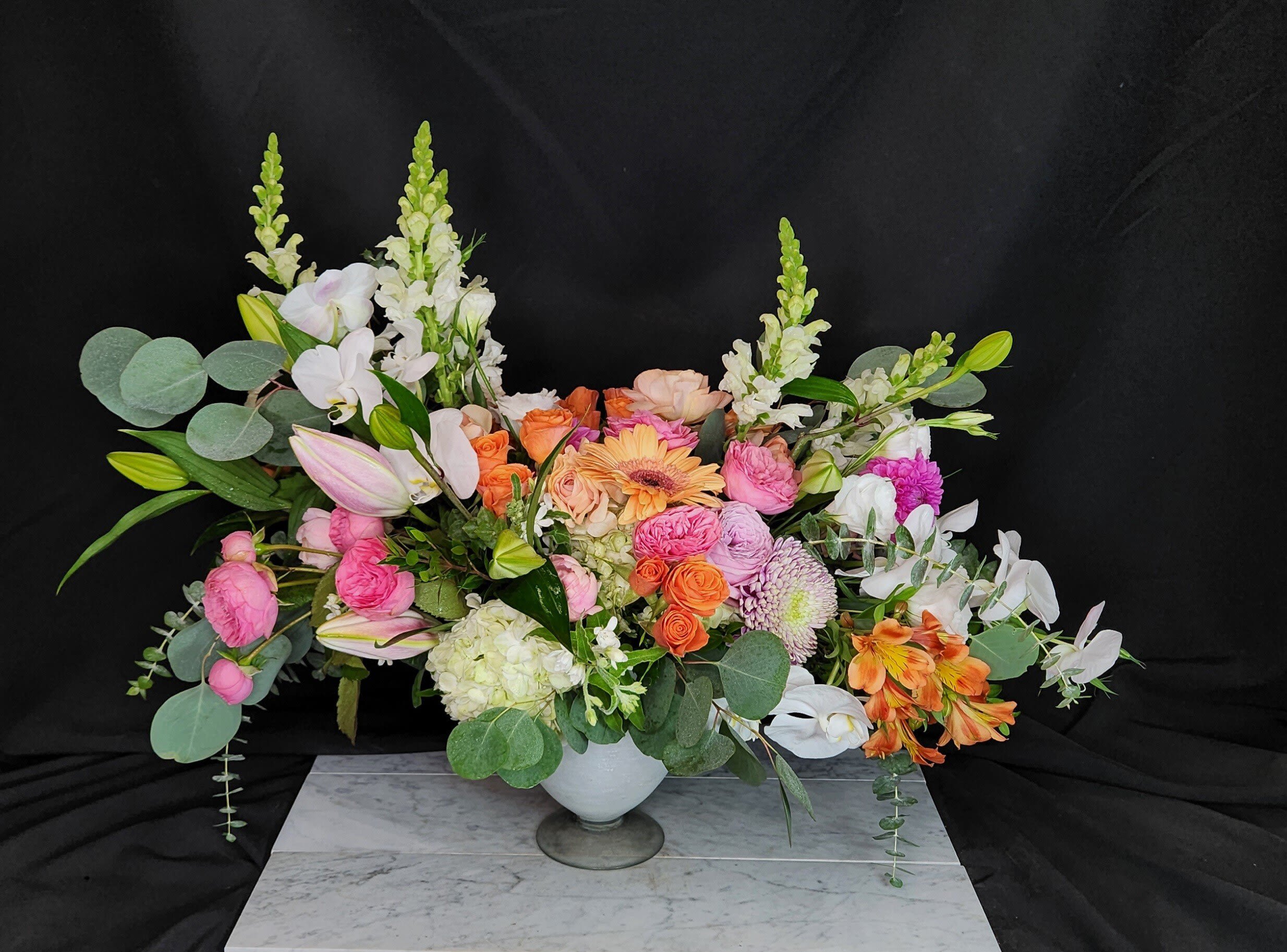 Regally Yours - Regally Yours is a lavish design including some of the most sought after flowers of the day.  Designed in a milky glass vase.  Includes Roses, Ranunculus,  Hydrangea, Phalaenopsis orchids and more, based on seasonality.  This will absolute bring a smile to the recipients face.  When you want to impress send this unique and lavish design.