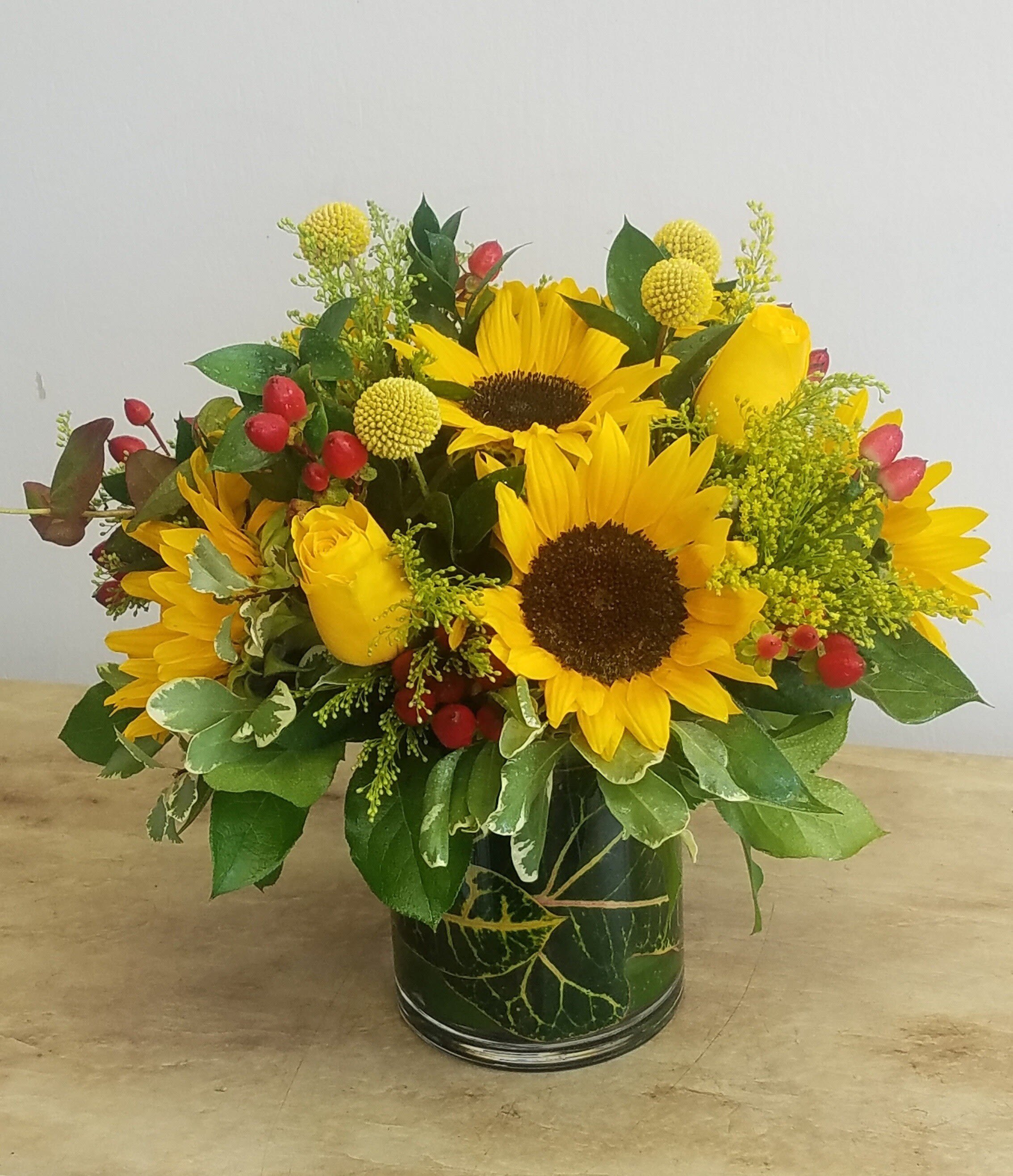 Sunflower and yellow rose arrangement in a glass vase