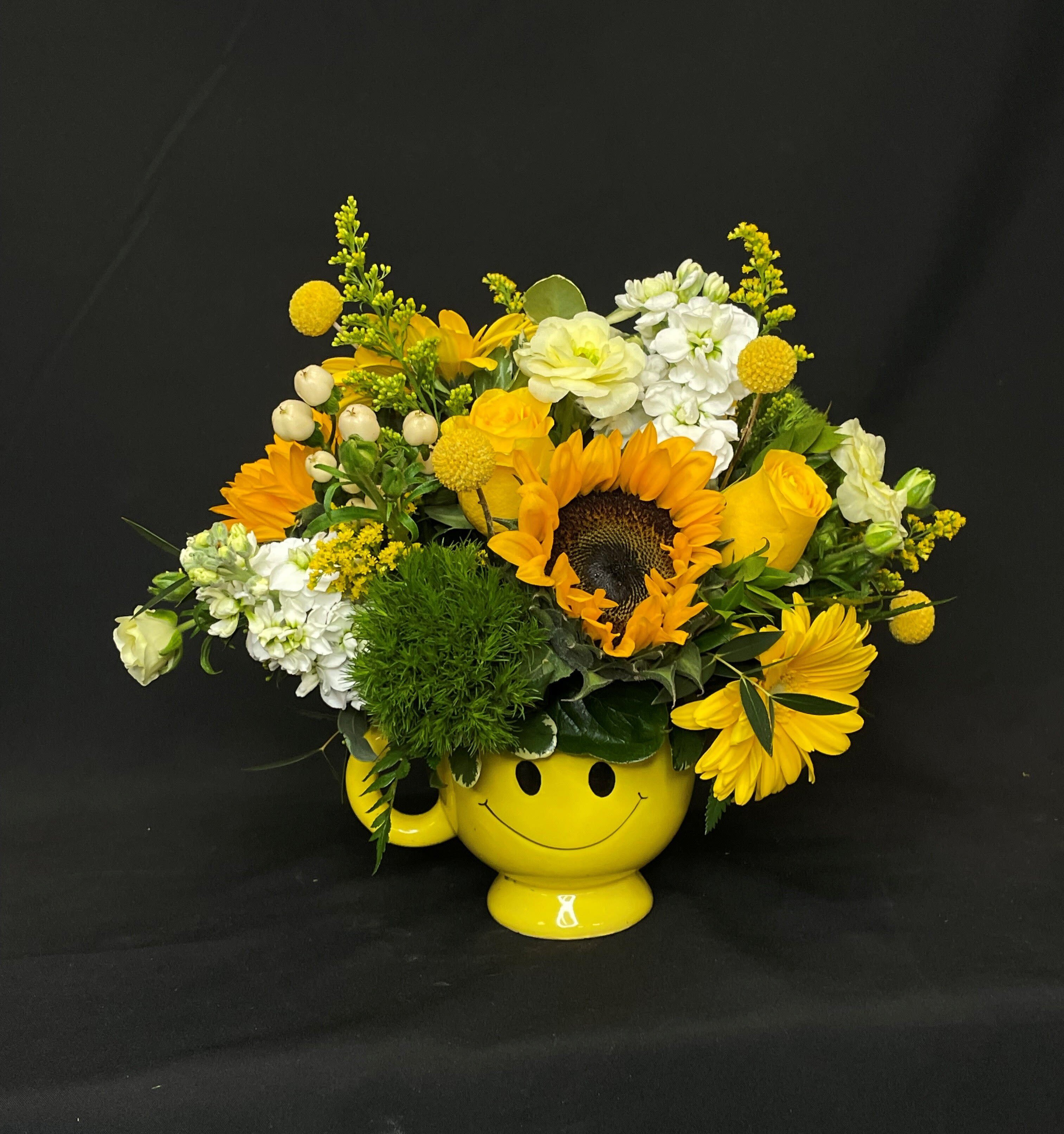 Yellow flower arrangement in a smiley-face mug