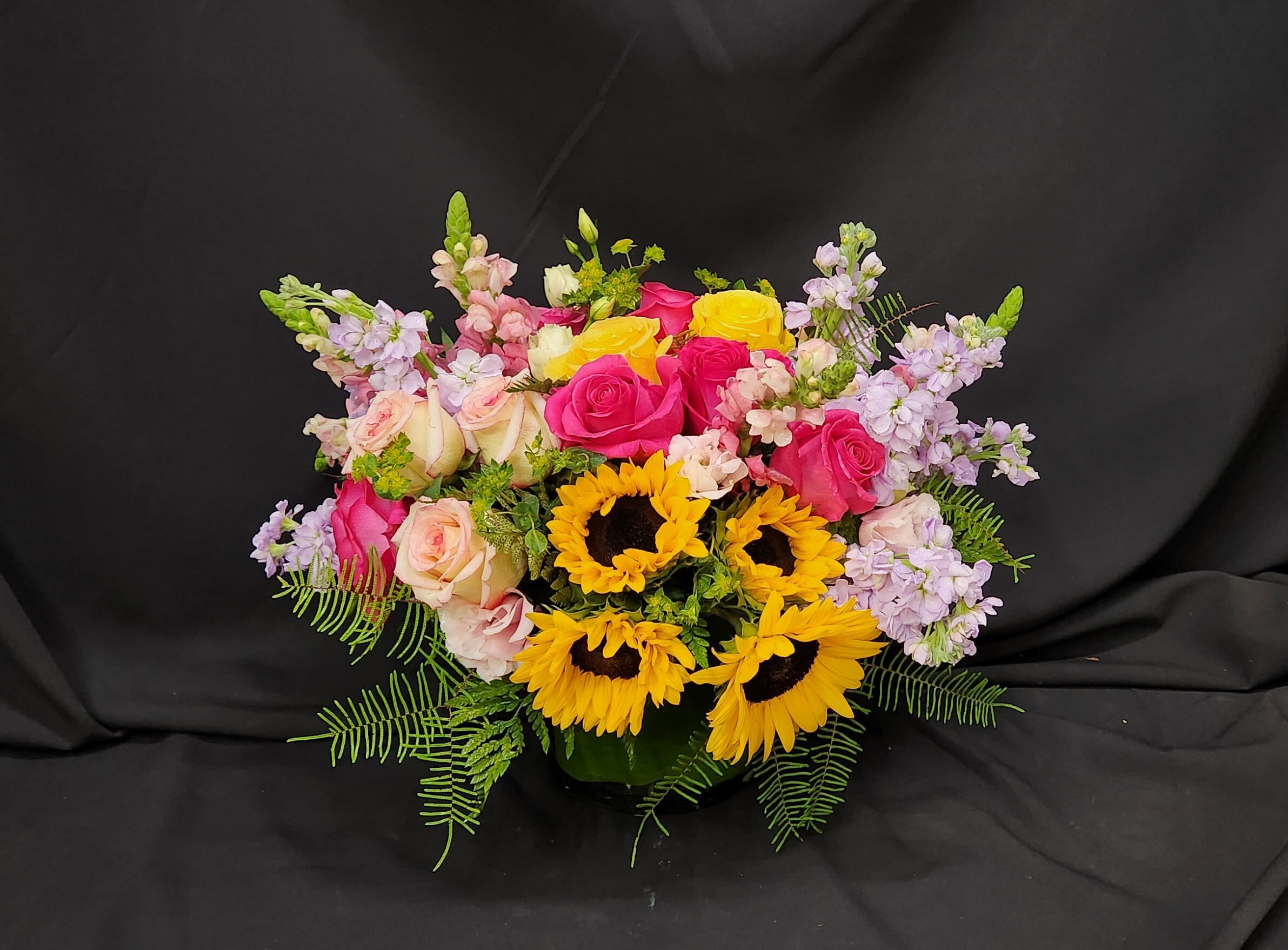 Mixed bouquet with roses, sunflowers, and lavender blooms in a vase
