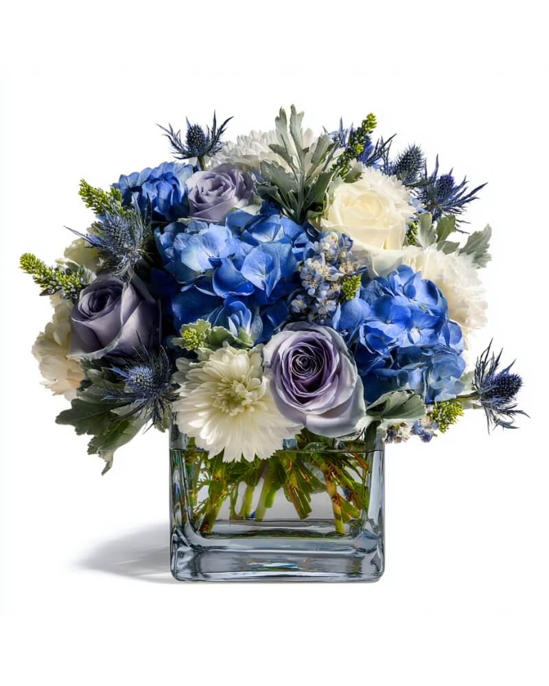 Blue and white flower arrangement in a square glass vase