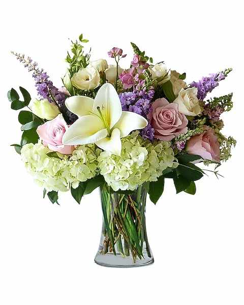 Bouquet of white lilies, roses, and purple flowers in a glass vase