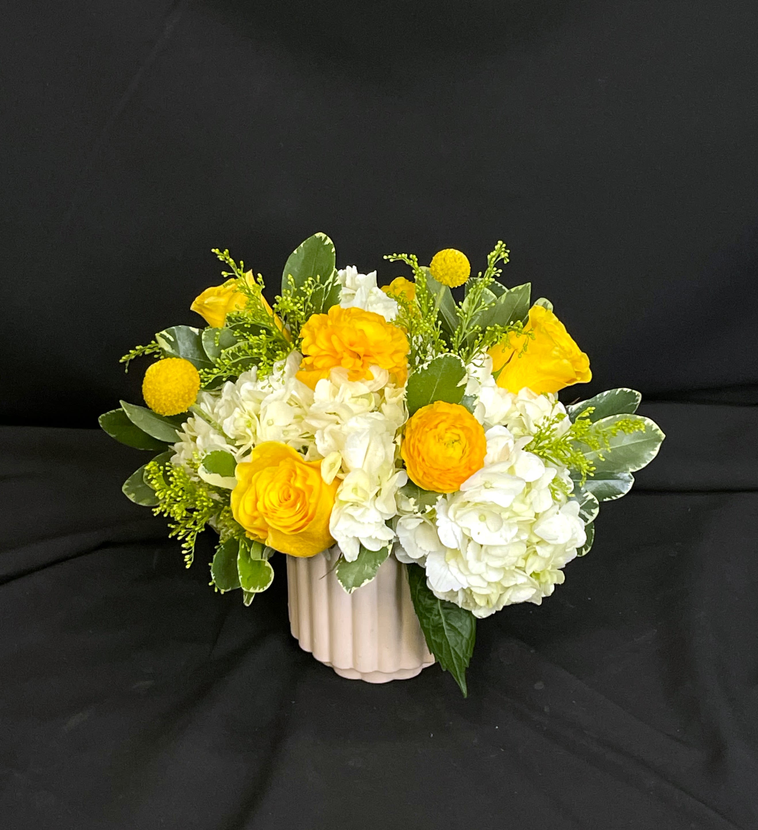 Madeline - Sweet Madeline marries a cute pink ceramic vase with lovely yellow peach and white blooms in a low and lush arrangement about 10 inches tall for the standard and deluxe options. She is petite but precious!