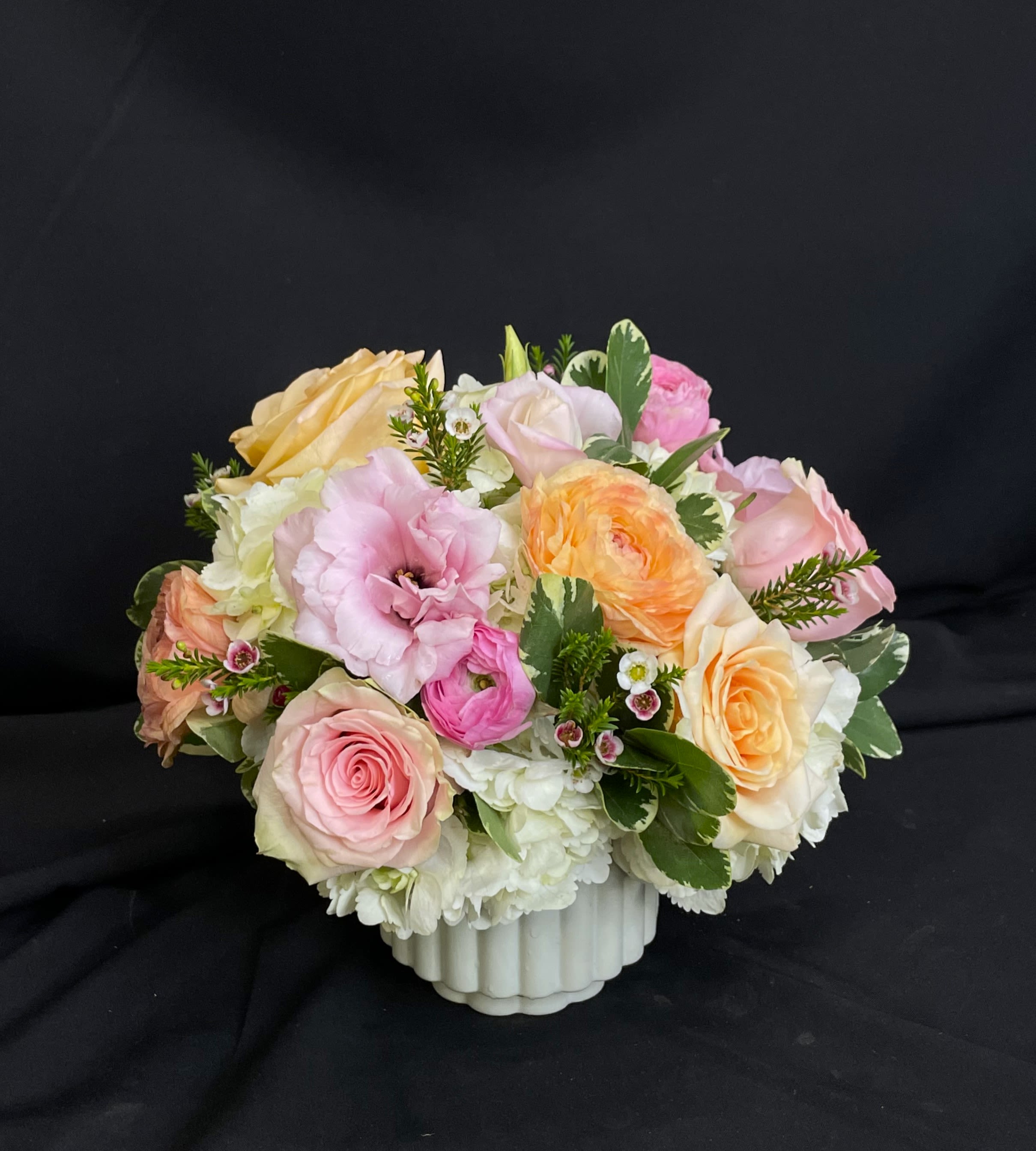 Penelope - Penelope is a mini version of our fan-favorite Mabeline. Lisianthus is added to the rose and ranunculus focused arrangement but the peach and pink color scheme remains the same. Penelope features a beautiful pale green fluted vase. Standard and deluxe versions are about 10 inches tall and the premium goes in a larger vase. 