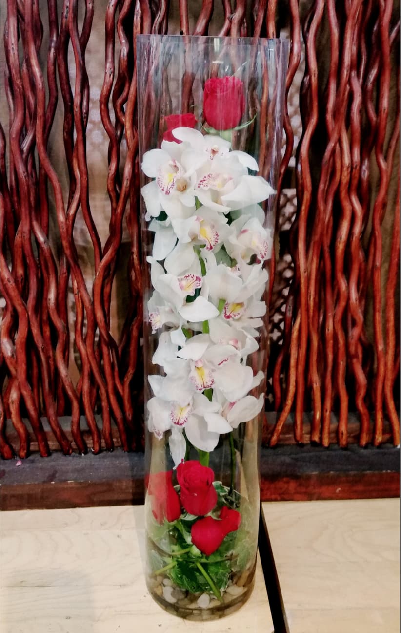 Tall glass vase with white orchids and red roses