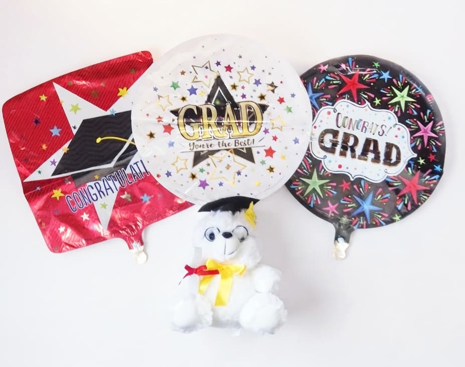 Three graduation balloons with a small teddy bear
