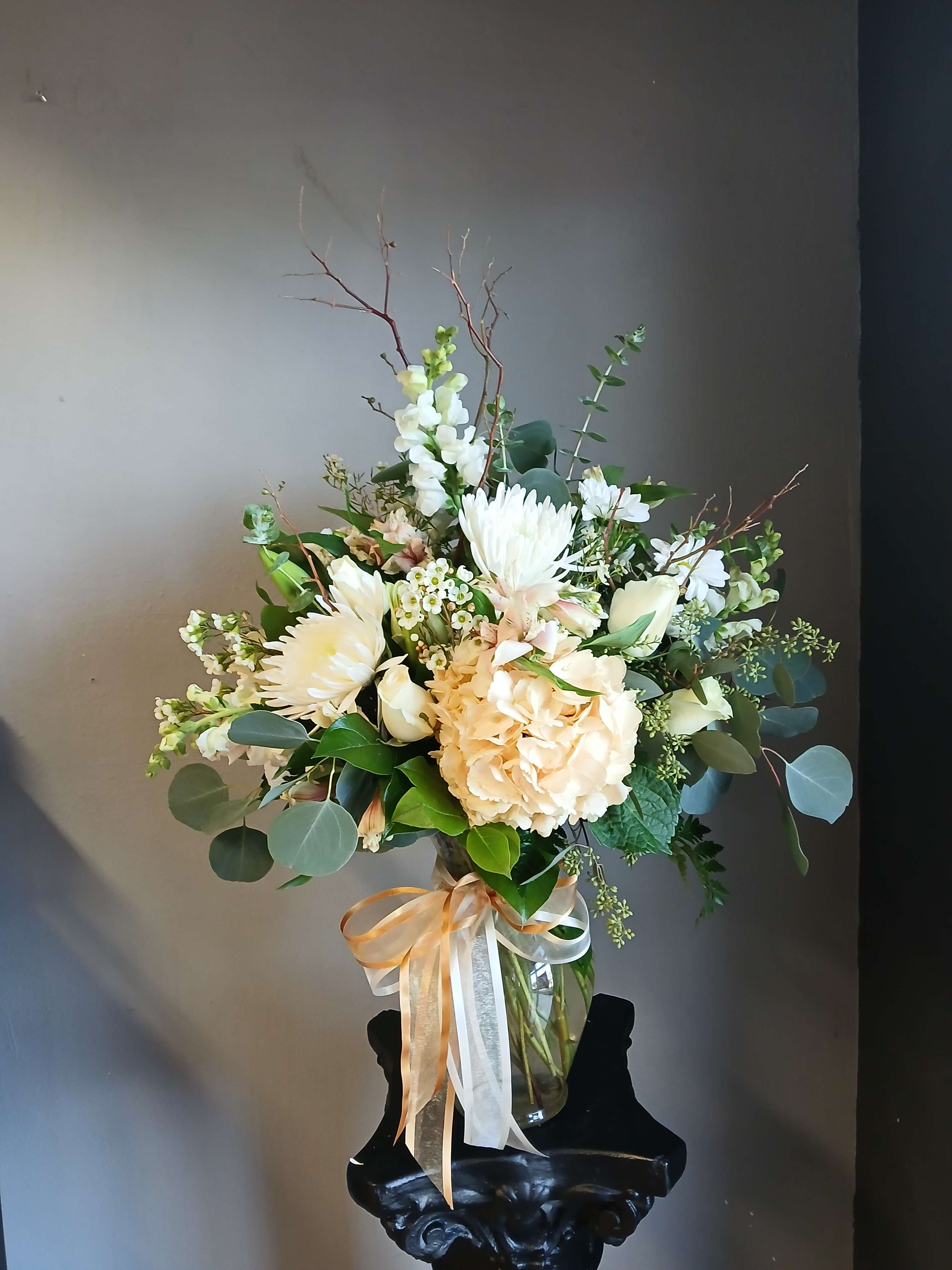 Cream and white bouquet in a clear glass vase with ribbon