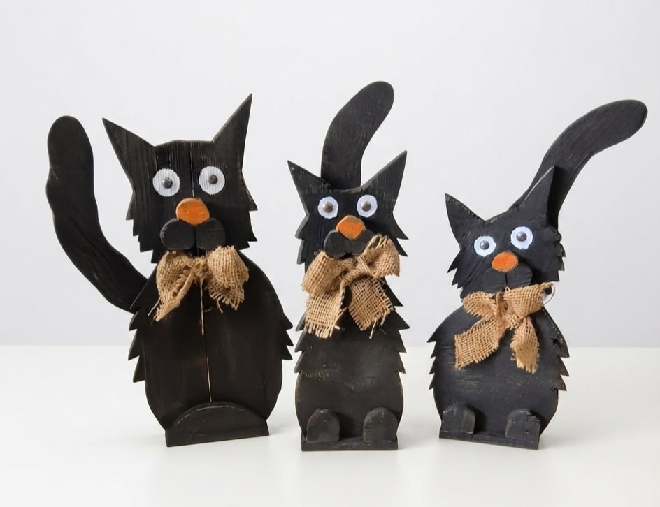 Three black cat figurines with burlap bows on a white background