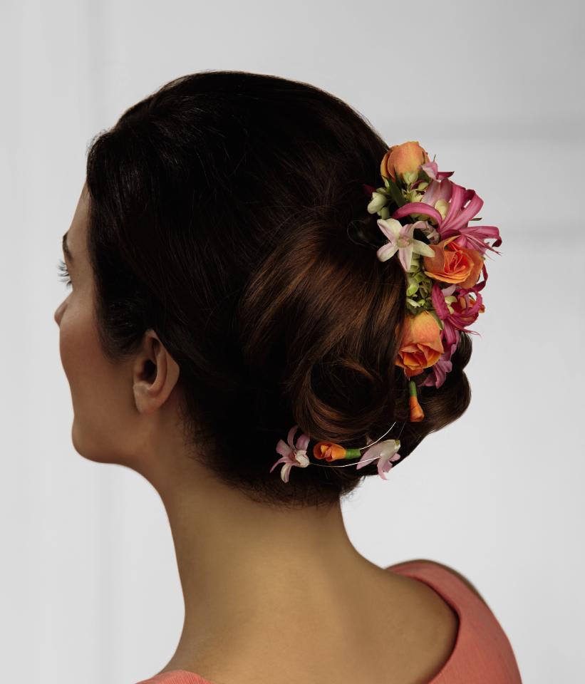 Woman wearing a floral hairpiece with pink and orange flowers