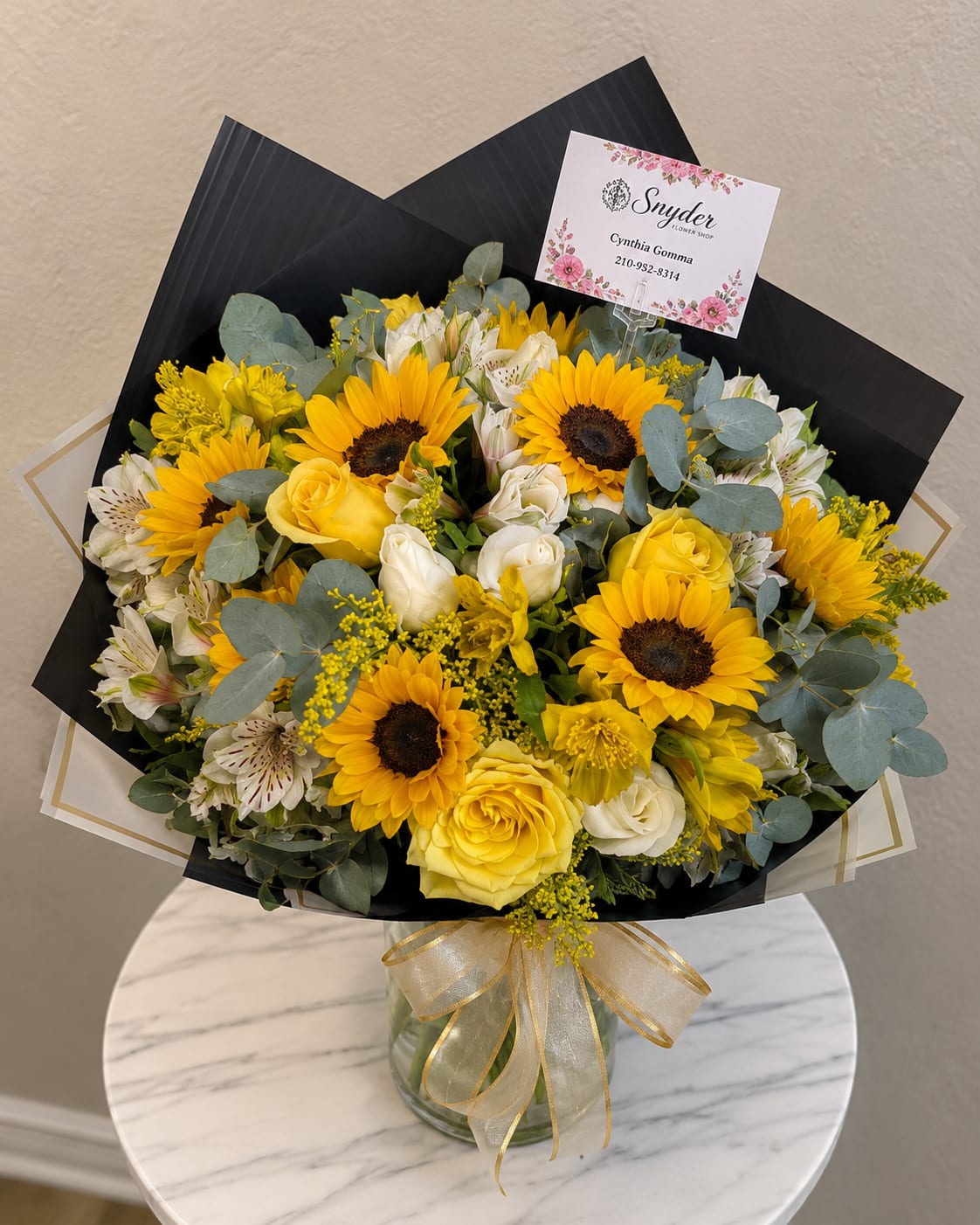 Bouquet of yellow sunflowers, yellow and white roses, and white alstroemeria in a glass vase