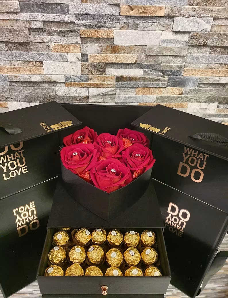 Black gift boxes with red roses and gold-wrapped chocolates