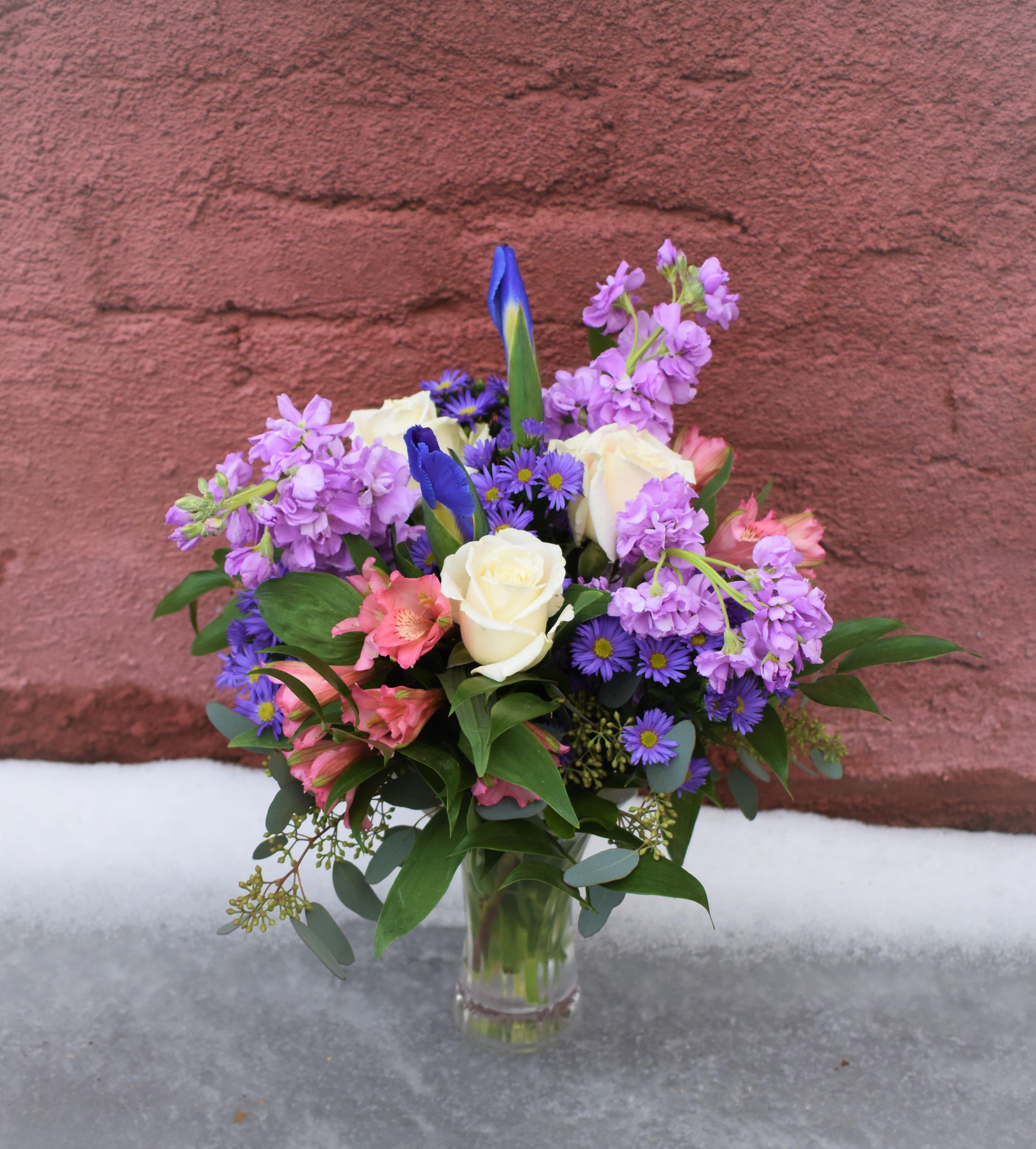 Bouquet of purple, pink, and white flowers in a clear glass vase