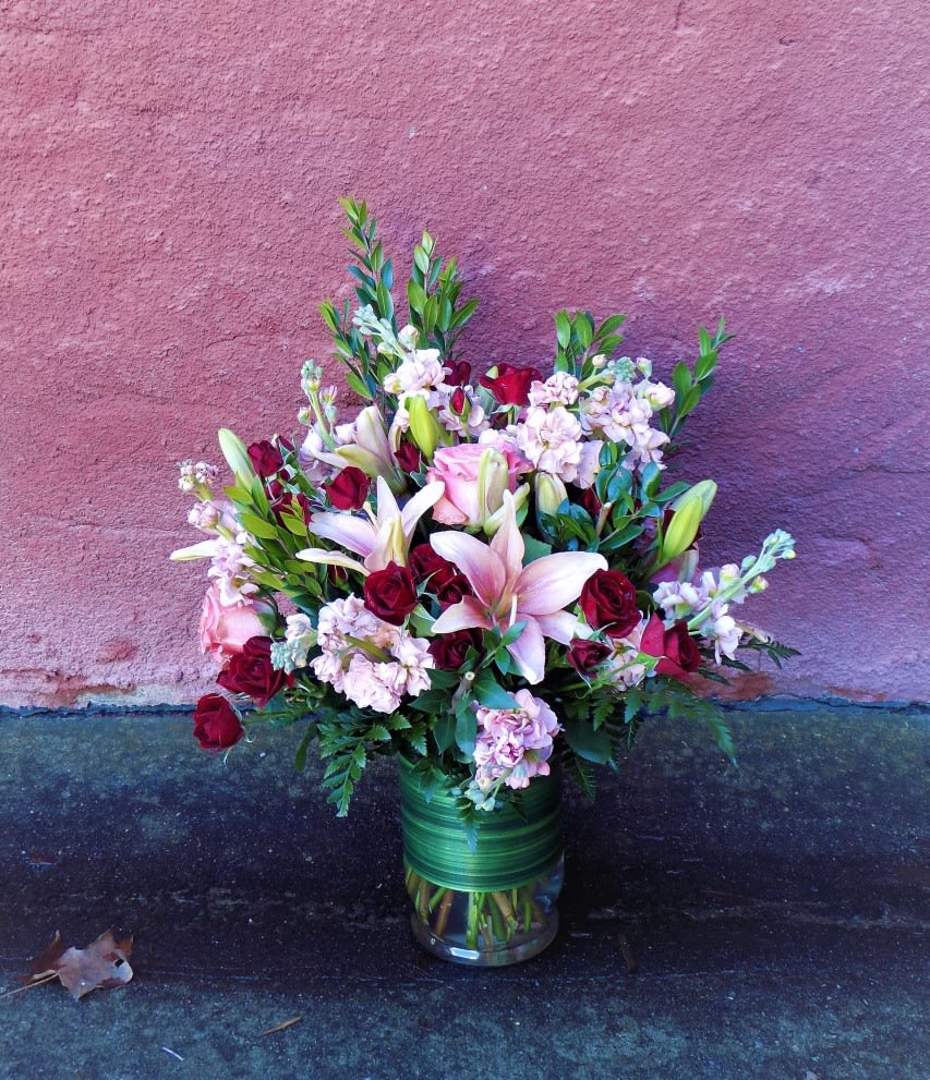 Bouquet of pink lilies and red roses in a glass vase