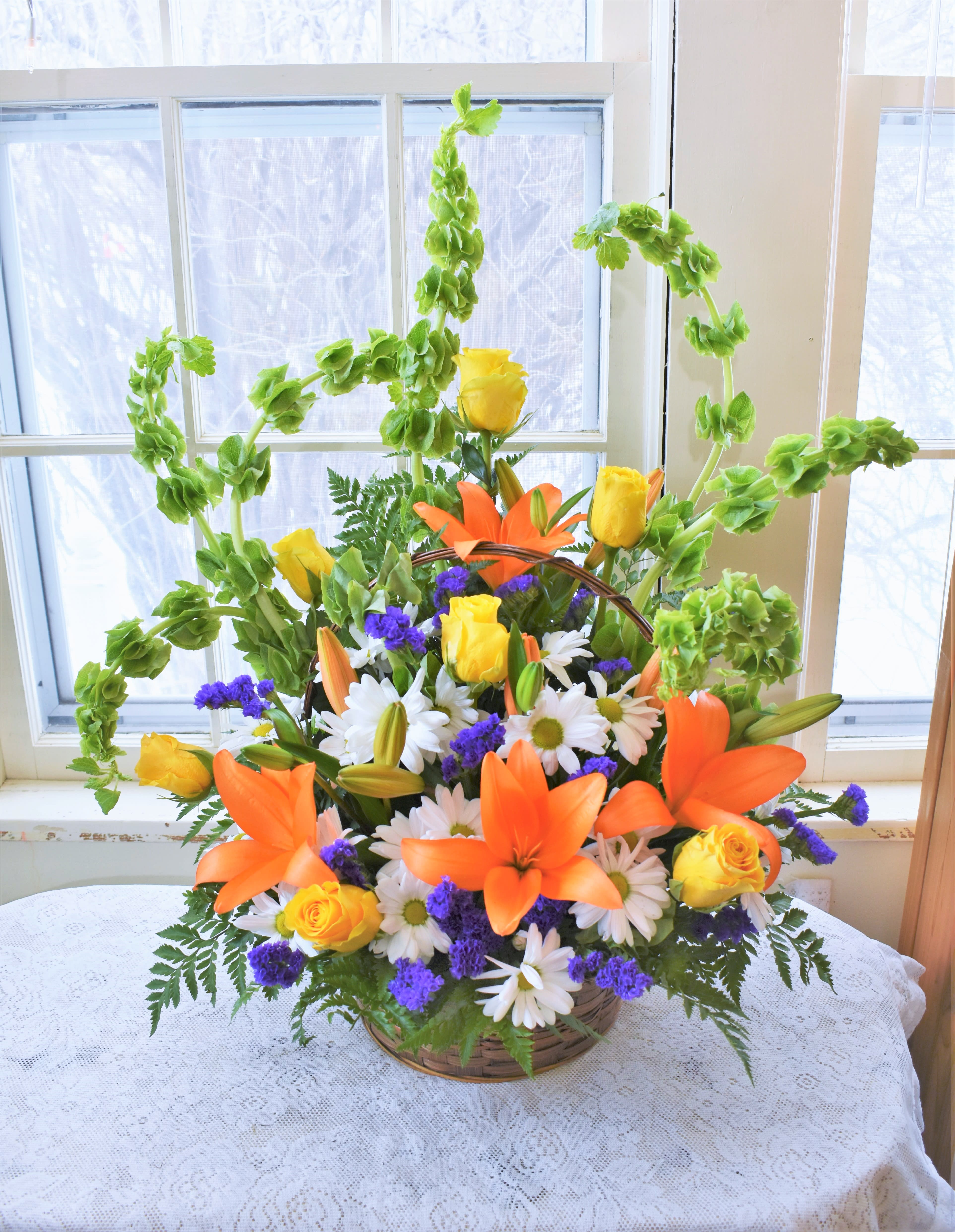 Basket arrangement of orange lilies, yellow roses, and white daisies