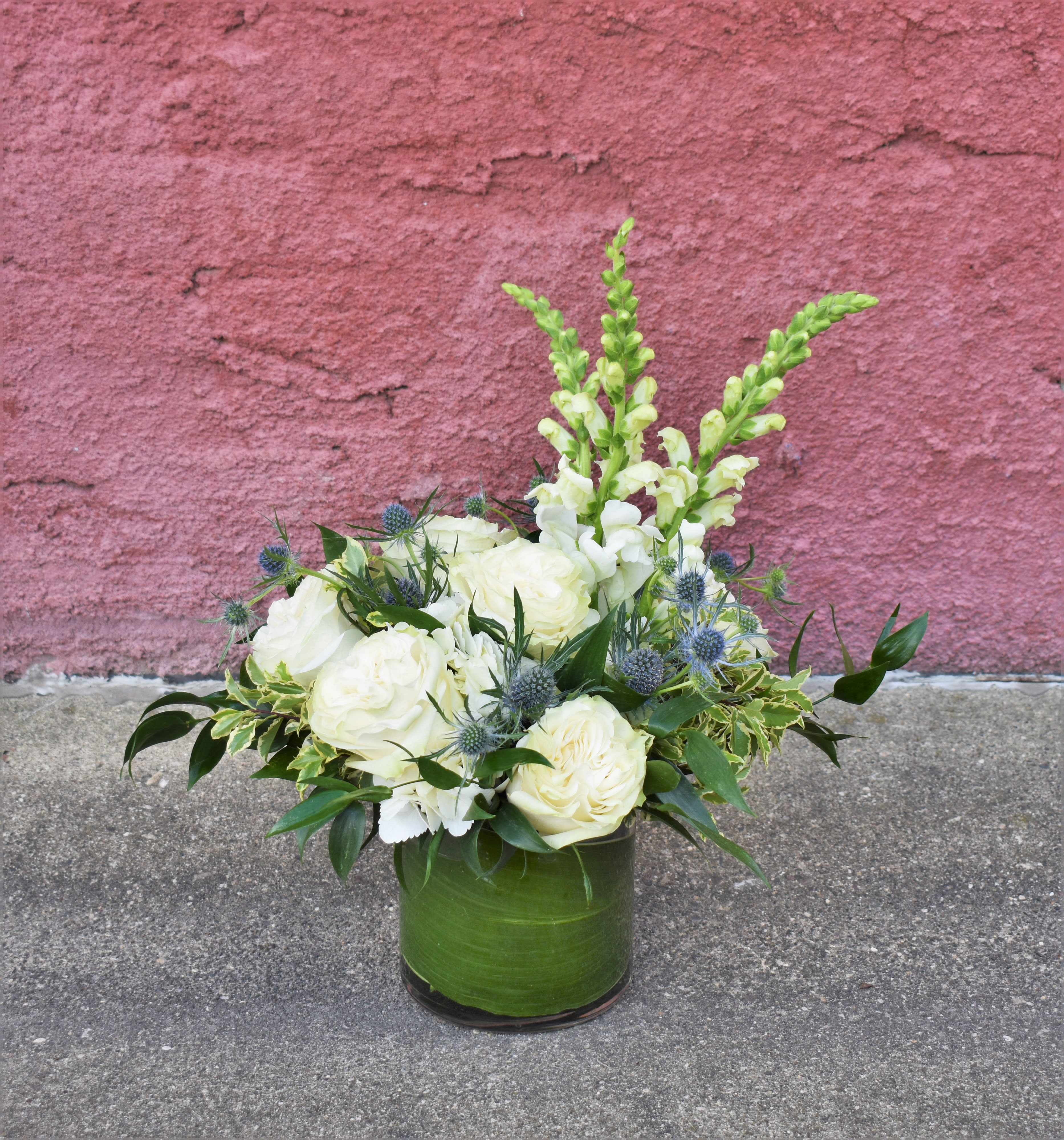 White roses and snapdragons in a green glass vase