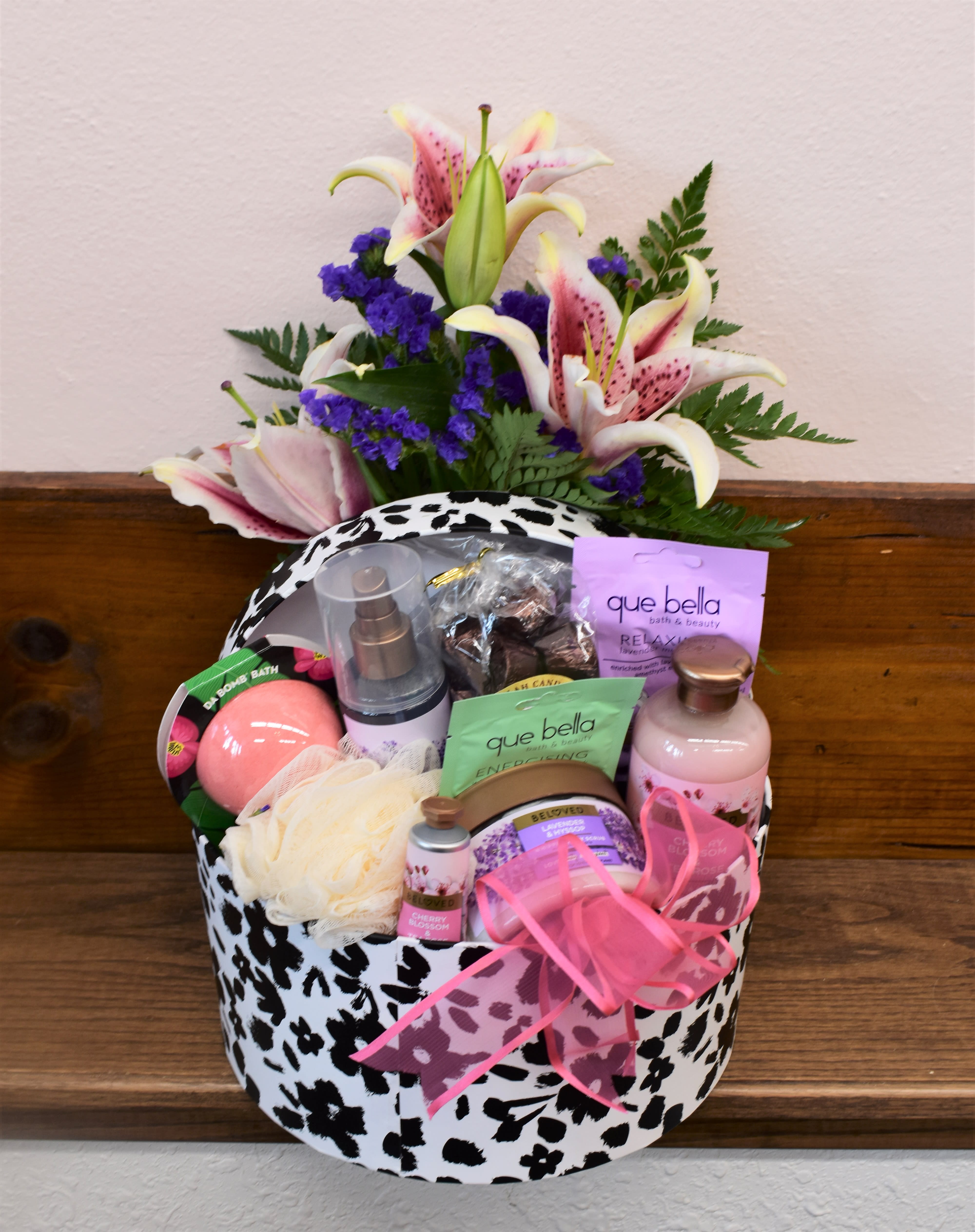 Gift basket with lilies and bath products in a black-and-white patterned box