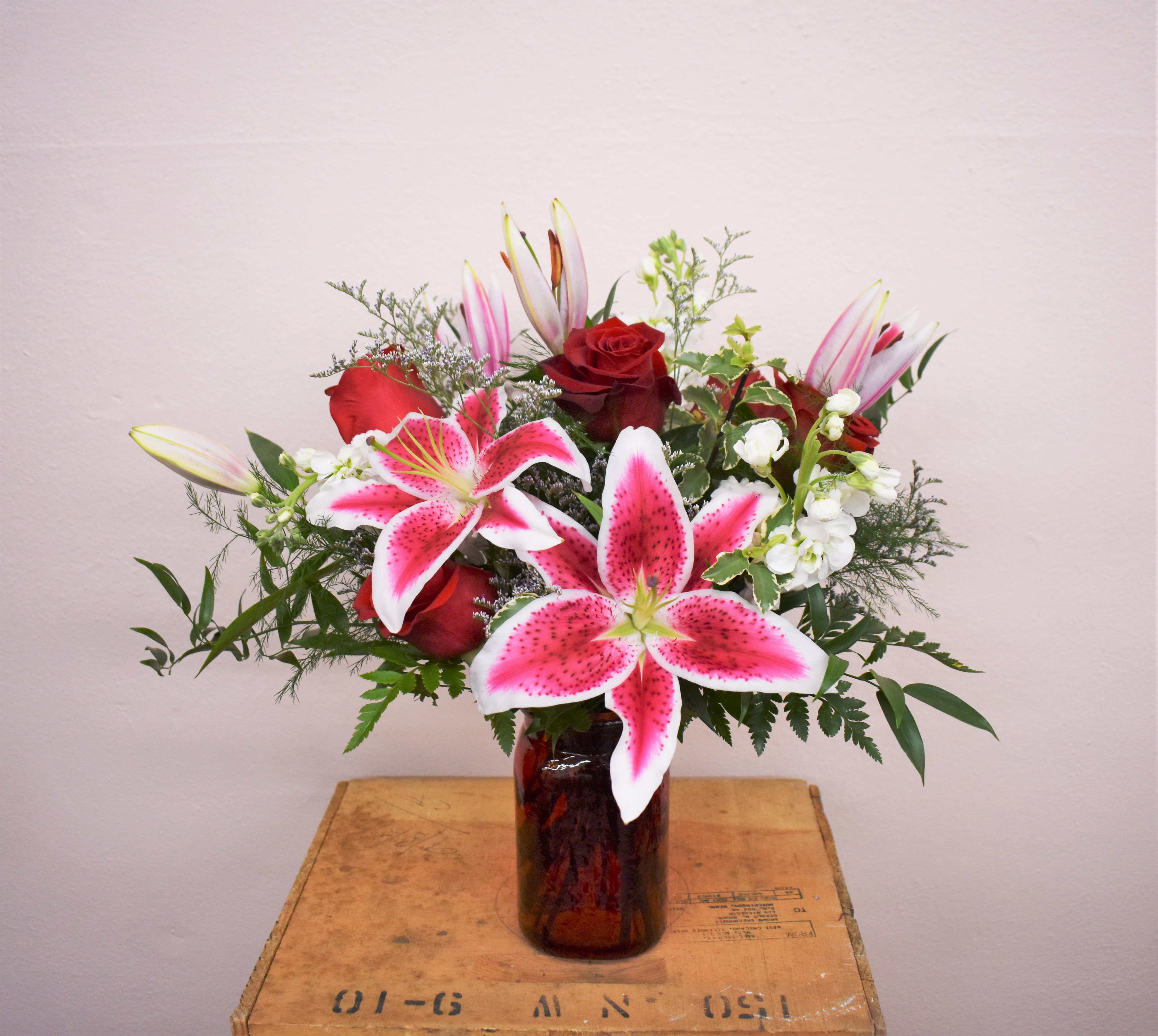 Bouquet of pink lilies and red roses in a glass vase