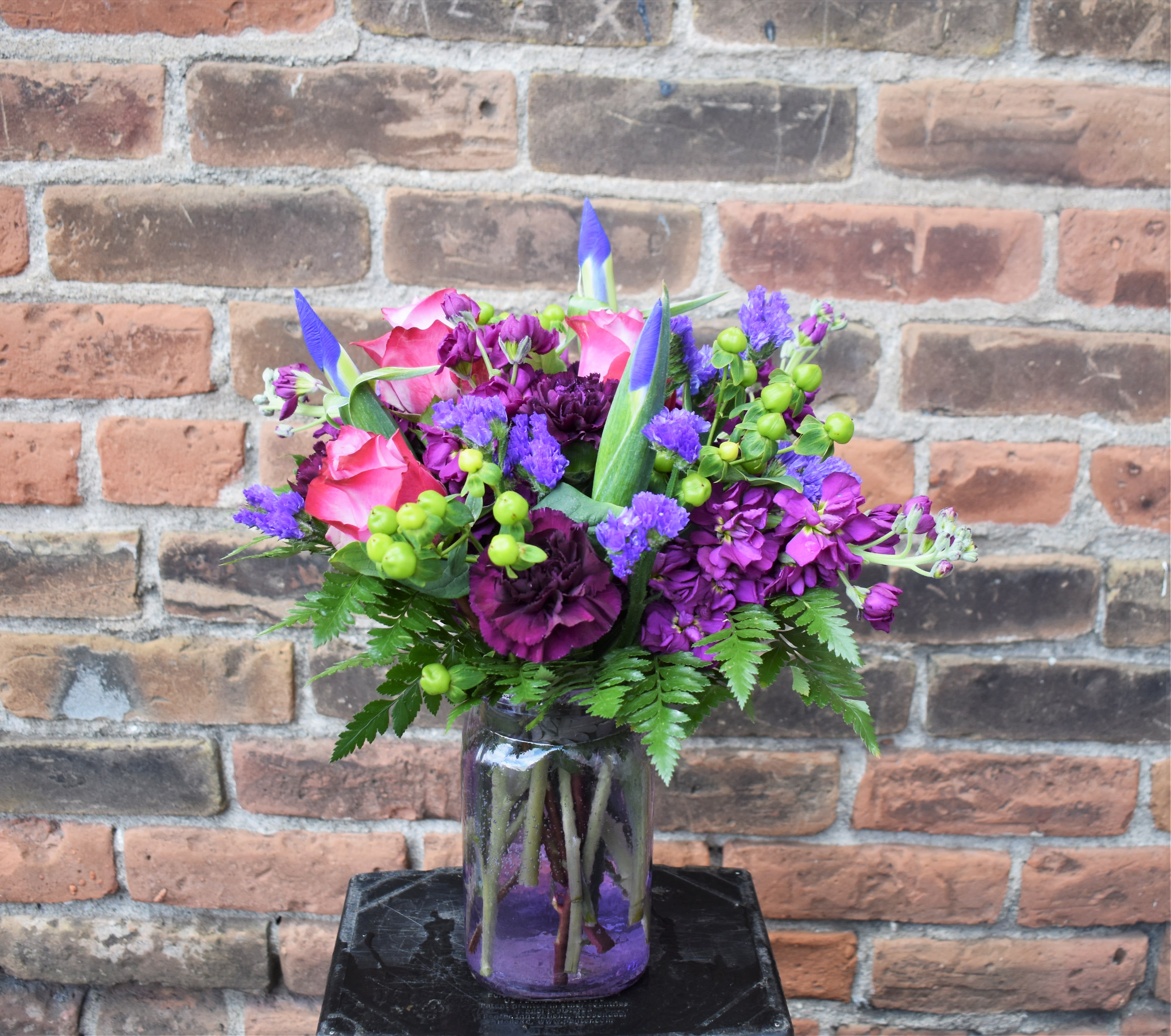 Pink and purple flower arrangement in a glass jar vase