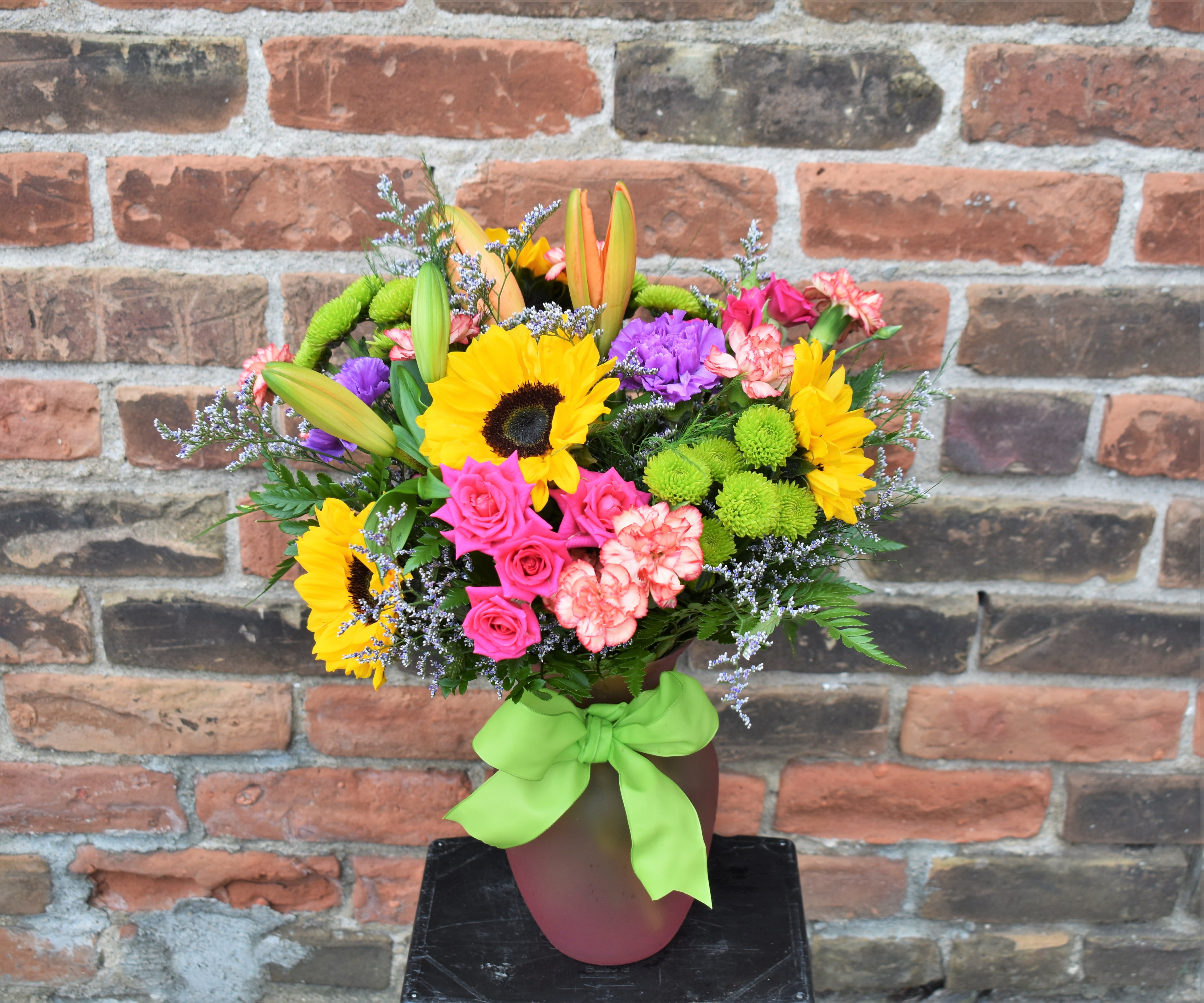 Colorful bouquet with sunflowers, roses, lilies, and carnations in a vase