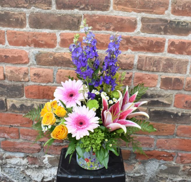 Skip Into Summer - Bright summery flowers of lilies, tulips, larkspur, hydrangea, Gerber daisies, and mums explode out of glass vase with wildflower detailing. The perfect way to celebrate any occasion! 