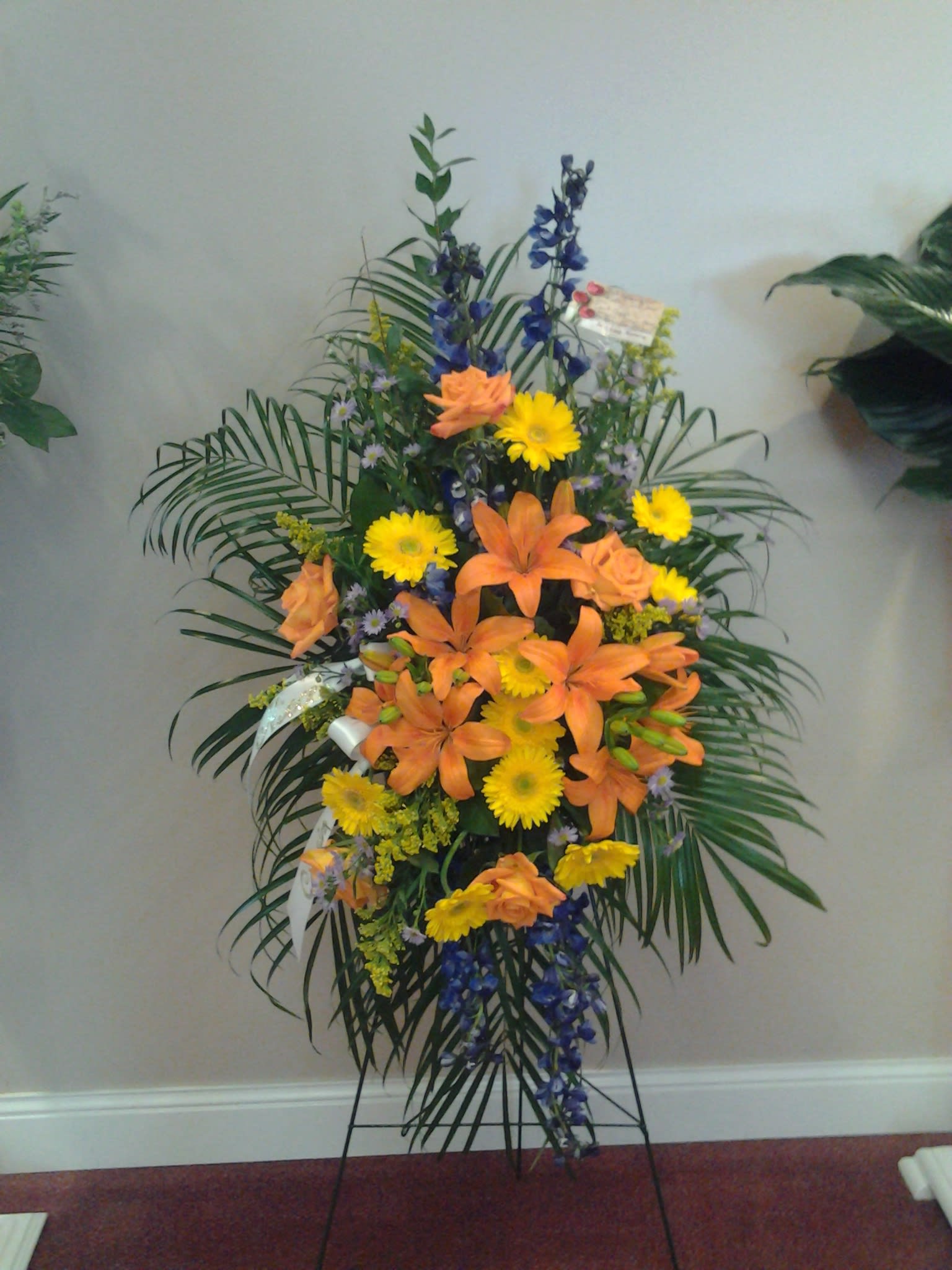 Tall standing floral spray with orange lilies and yellow daisies