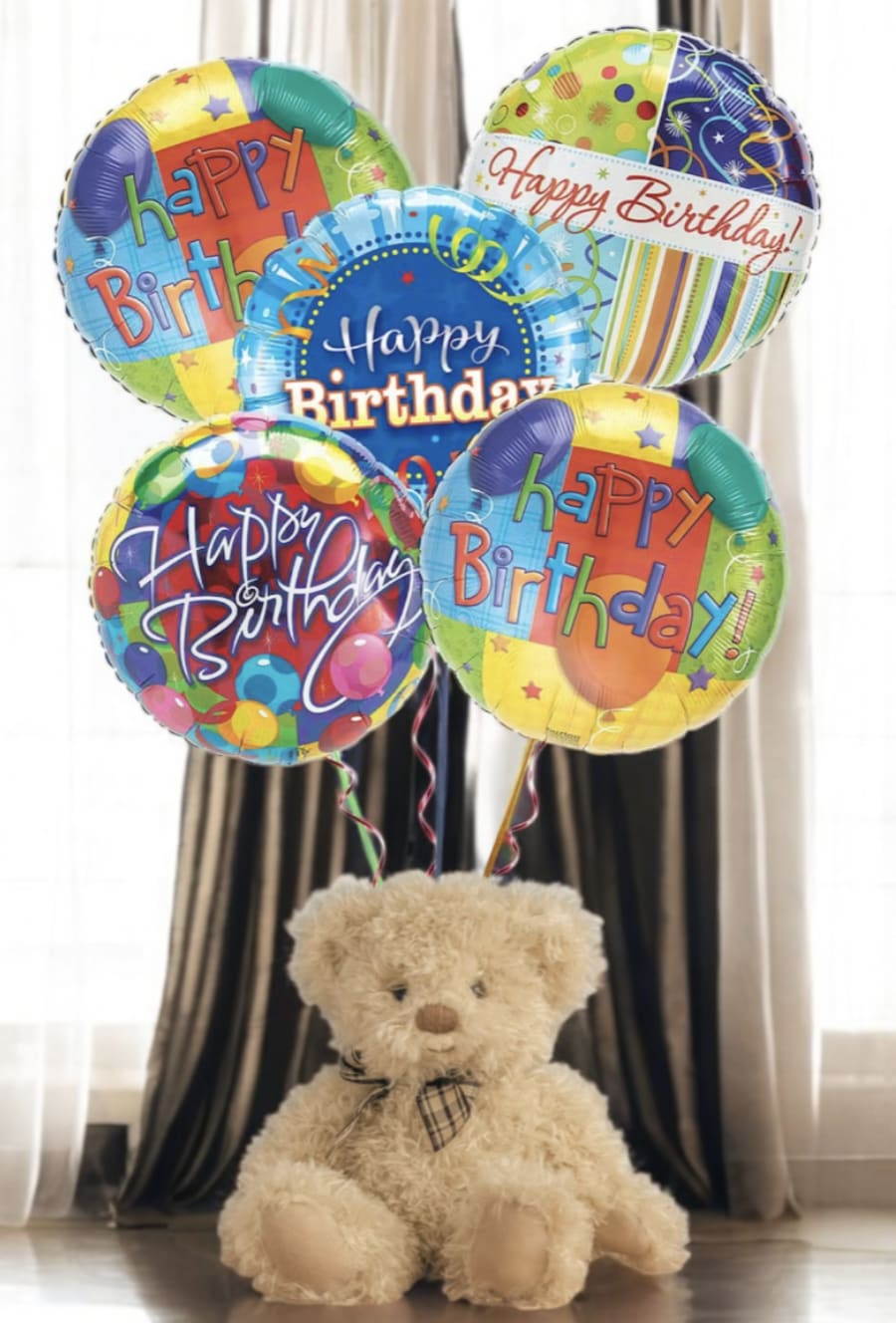 Birthday balloons above a teddy bear