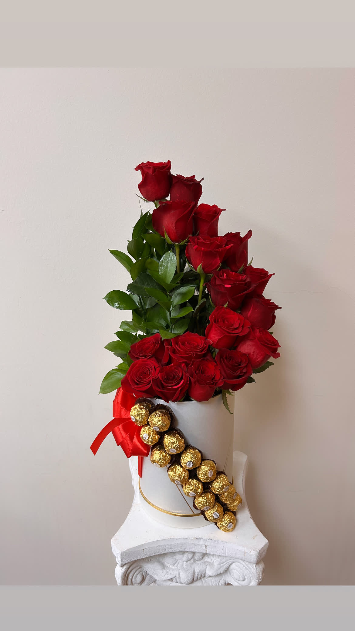 Red roses in a white hatbox with a red ribbon and Ferrero Rocher chocolates