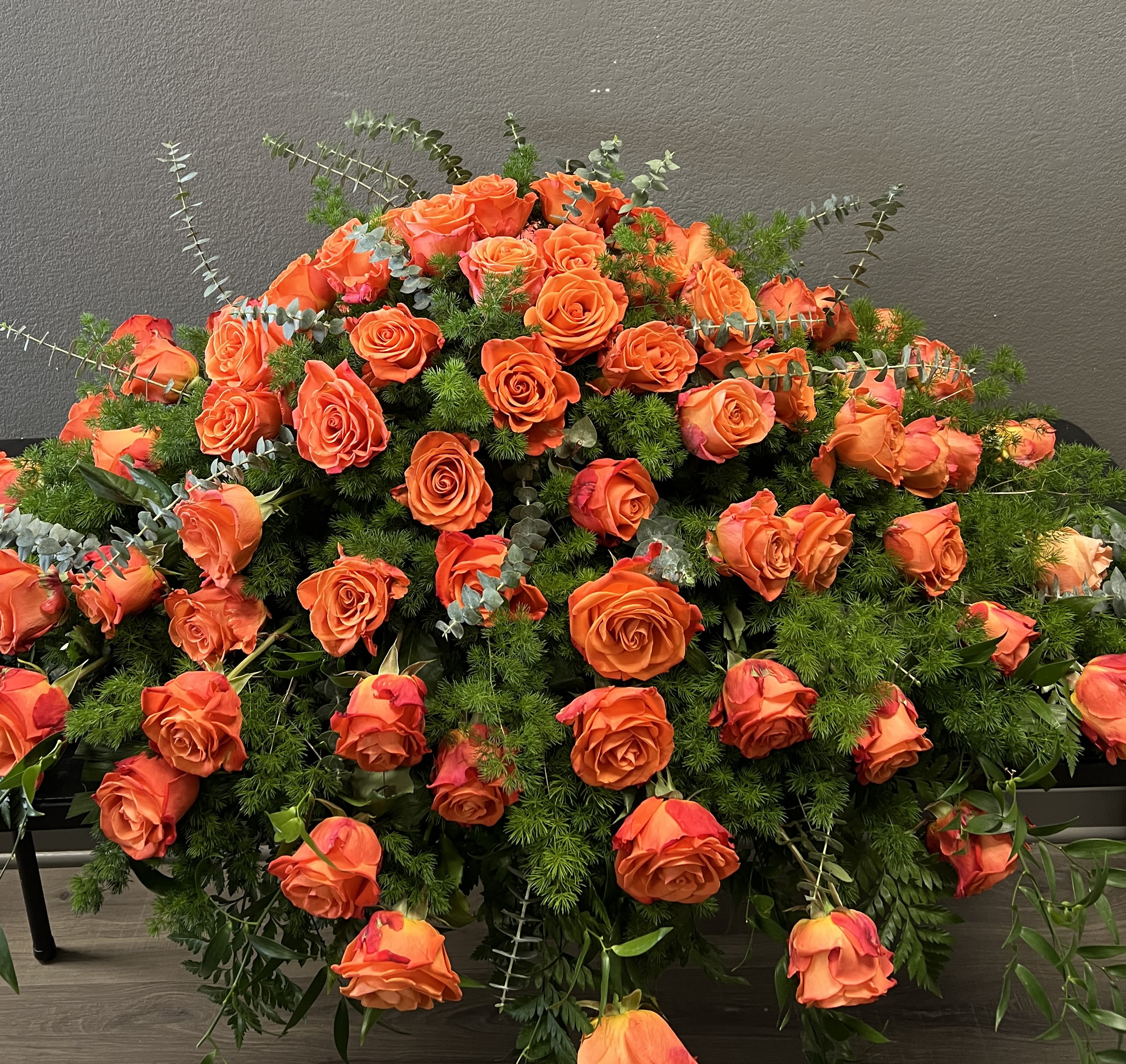 Large arrangement of orange roses with mixed greenery