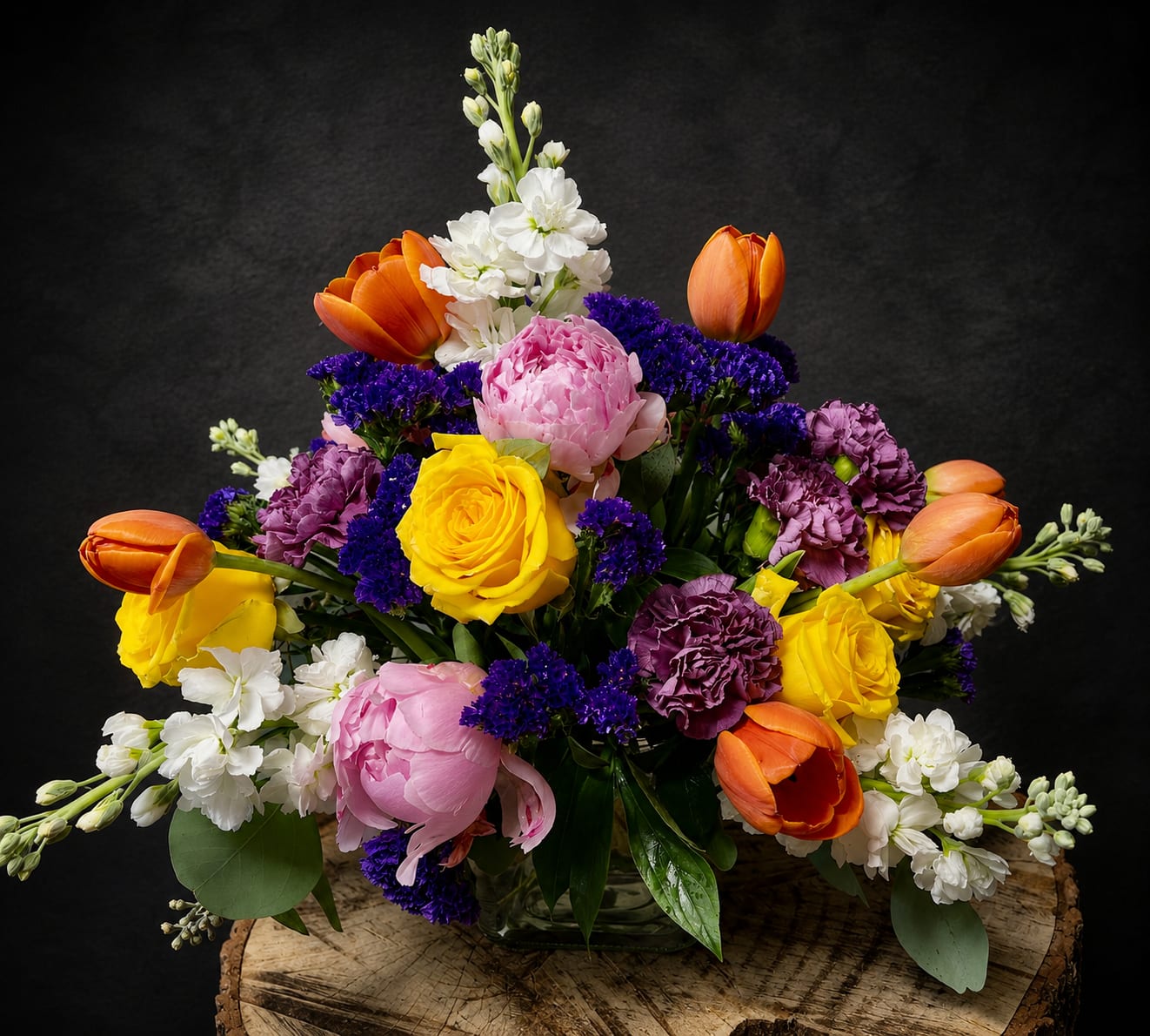 You’ve Been So So Good To Me - A radiant, garden-style flower arrangement that reads like a joyful celebration in bloom - perfect as a birthday bouquet, anniversary arrangement, or "thinking of you" surprise. You've Been So So Good To Me mixes pink peonies and orange tulips with bright yellow roses, purple carnations and white stock to create a full, rounded display that immediately lifts the room and the recipient's spirits. This is the kind of bouquet that makes someone feel genuinely seen and celebrated, whether you're saying thank you, congratulations, I'm sorry, or simply sending love.  