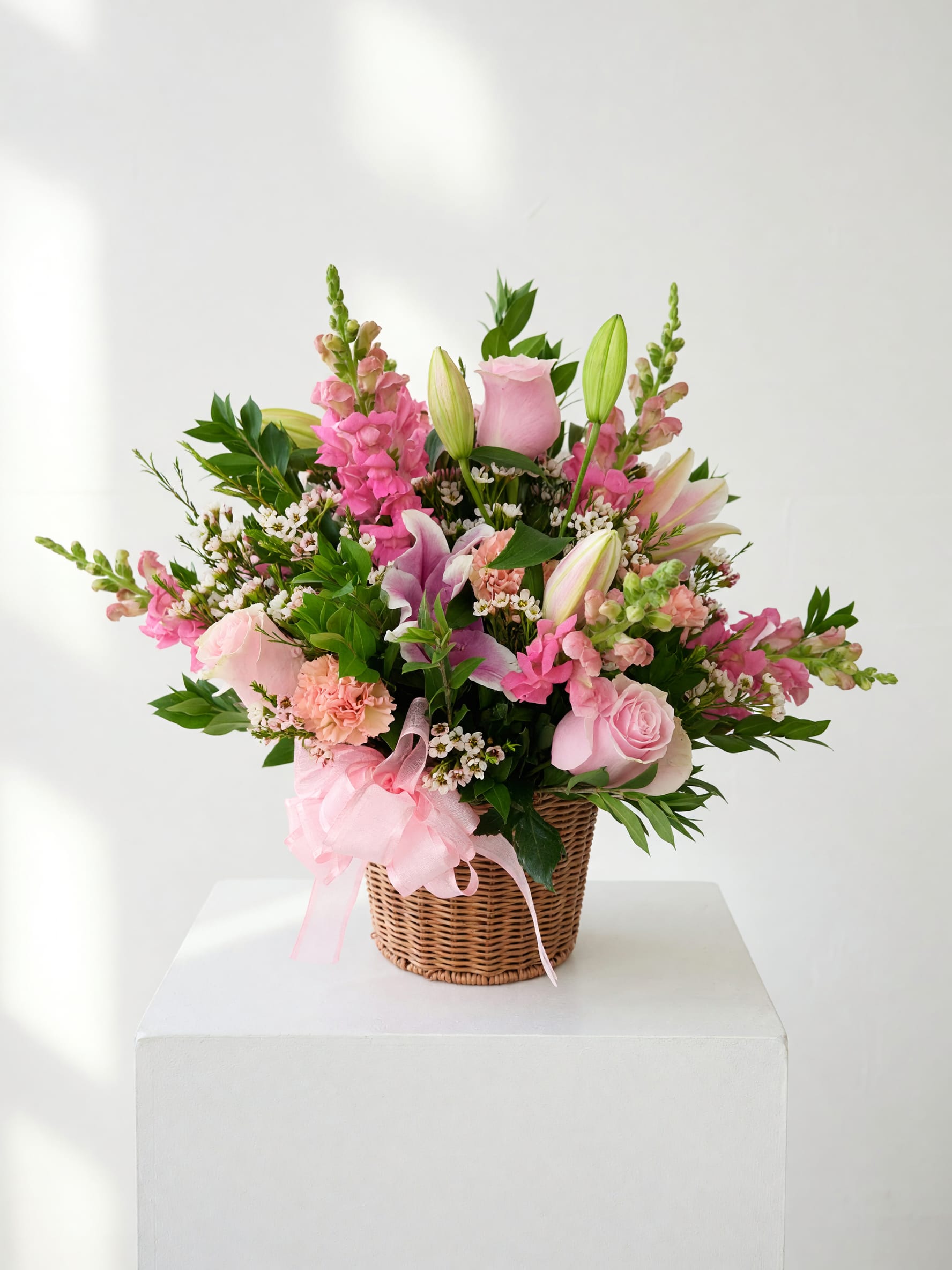 Pink floral basket arrangement with roses, lilies, and snapdragons