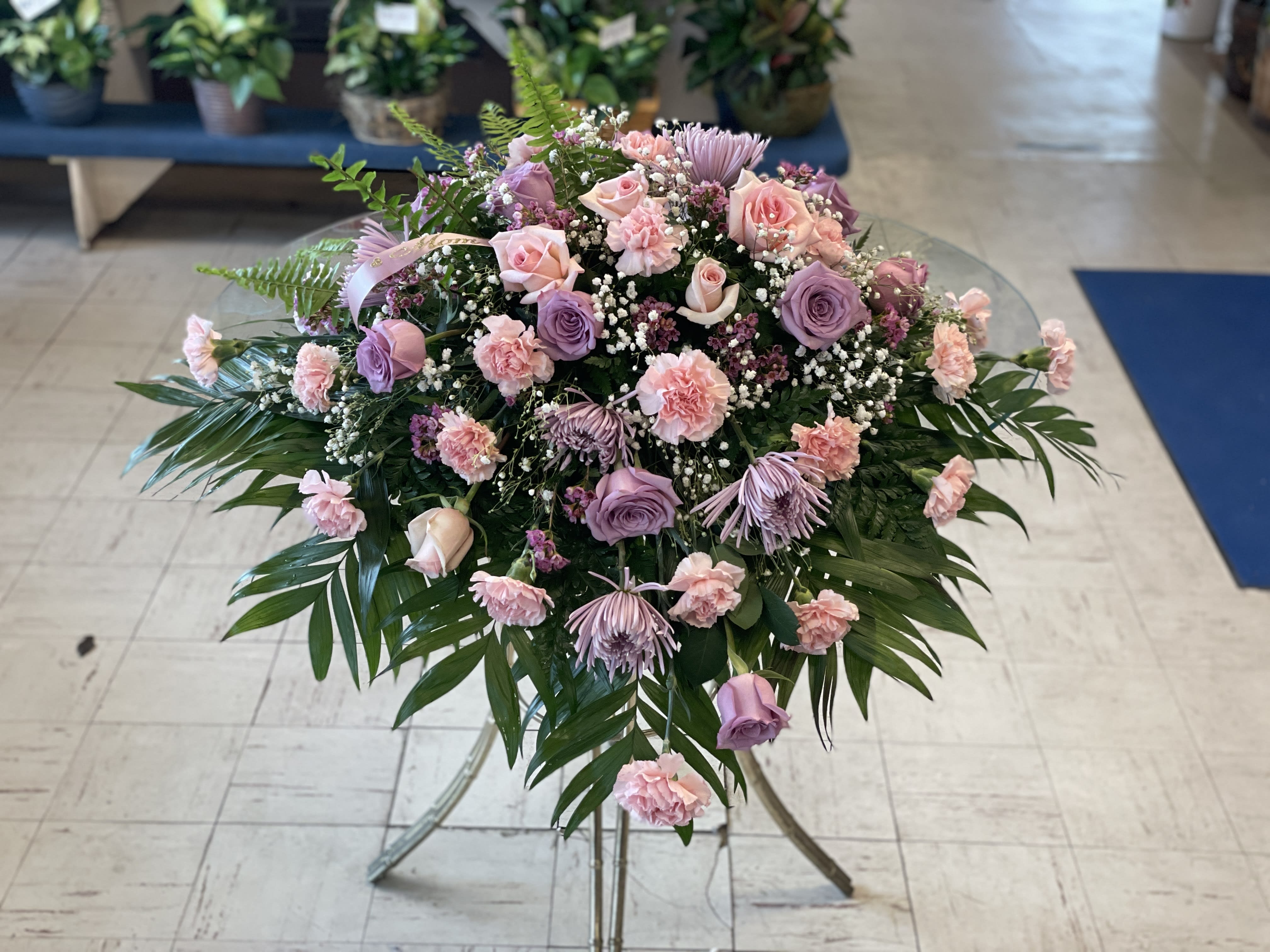 Pink and lavender floral spray on a stand with palm fronds