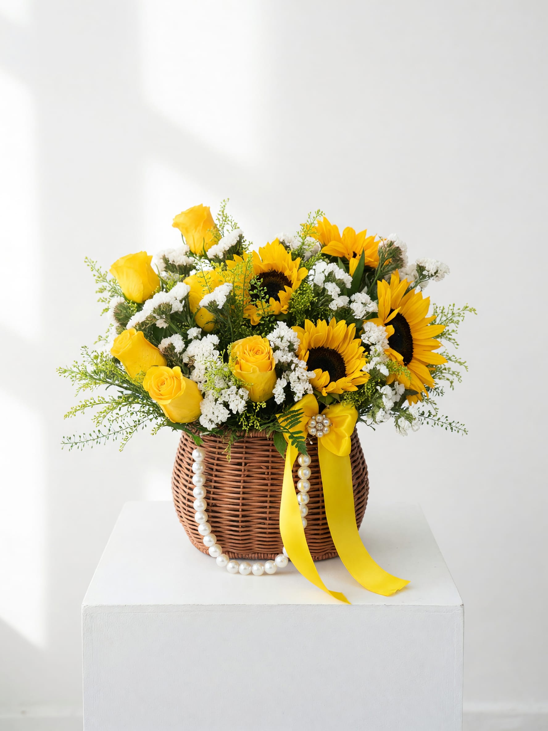 Yellow roses and sunflowers in a wicker basket with a yellow ribbon