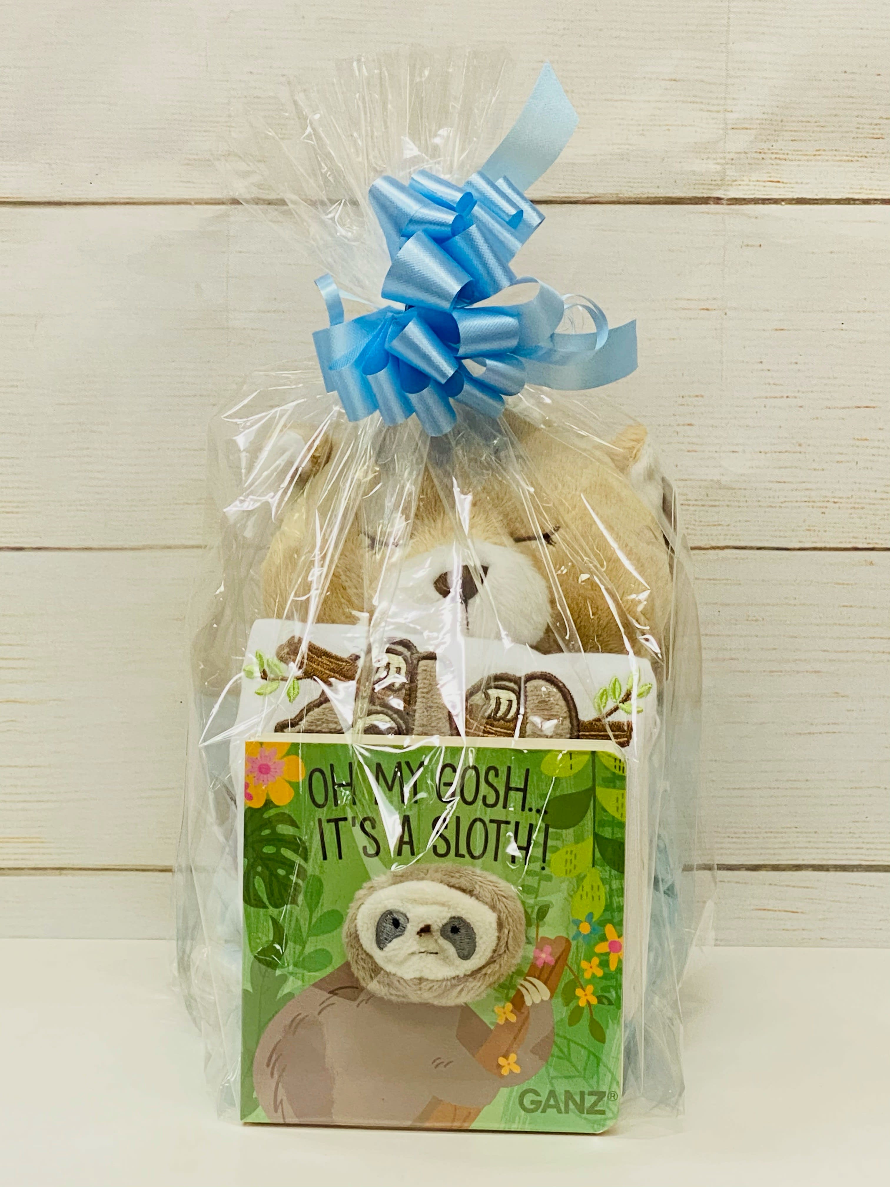 Stuffed animal and sloth-themed children’s book wrapped in clear cellophane with a blue ribbon bow