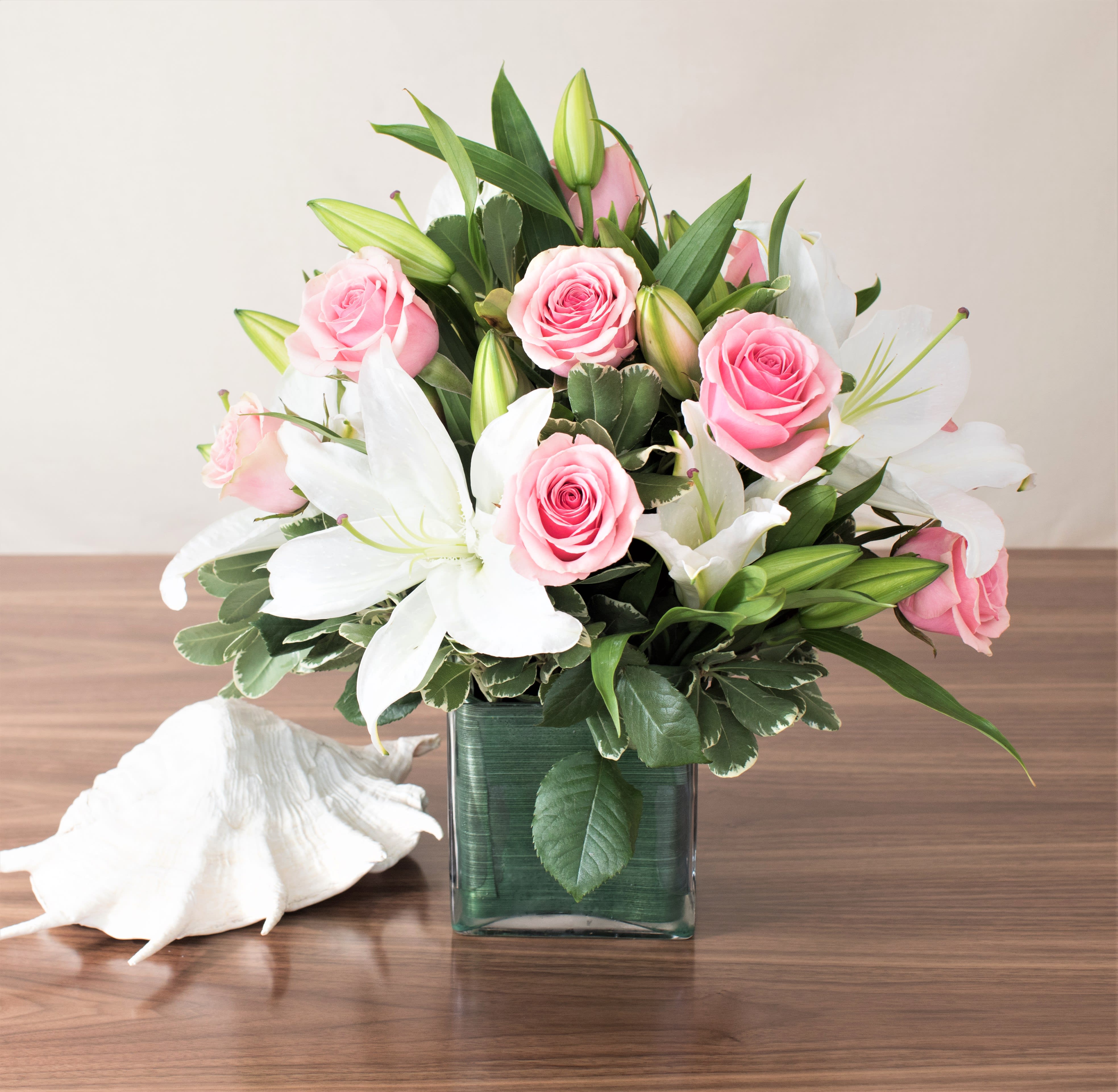 Classic Rose &amp; Lily Cube - A truly gorgeous piece featuring stunning stargazer lilies and a dozen premium roses, this arrangement has long been one of our most popular items. Perfect for a coffee table, end table, dining room, or desk, it adds elegance and beauty to any space.  Key Features:  Stargazer Lilies: Known for their striking appearance and delightful fragrance, these lilies add a touch of sophistication.  Premium Roses: Includes a dozen premium roses, carefully selected for their beauty and freshness.  Versatile Placement: Ideal for enhancing the aesthetic of coffee tables, end tables, dining rooms, or desks.  Popular Choice: One of our most beloved items, known for its timeless beauty and elegance. Elegant Design: Expertly arranged to create a harmonious blend of colors and textures, making it a standout piece in any setting.  Elevate your decor with our Stargazer Lilies and Premium Roses Arrangement, and enjoy the elegance and charm it brings to your home or office.