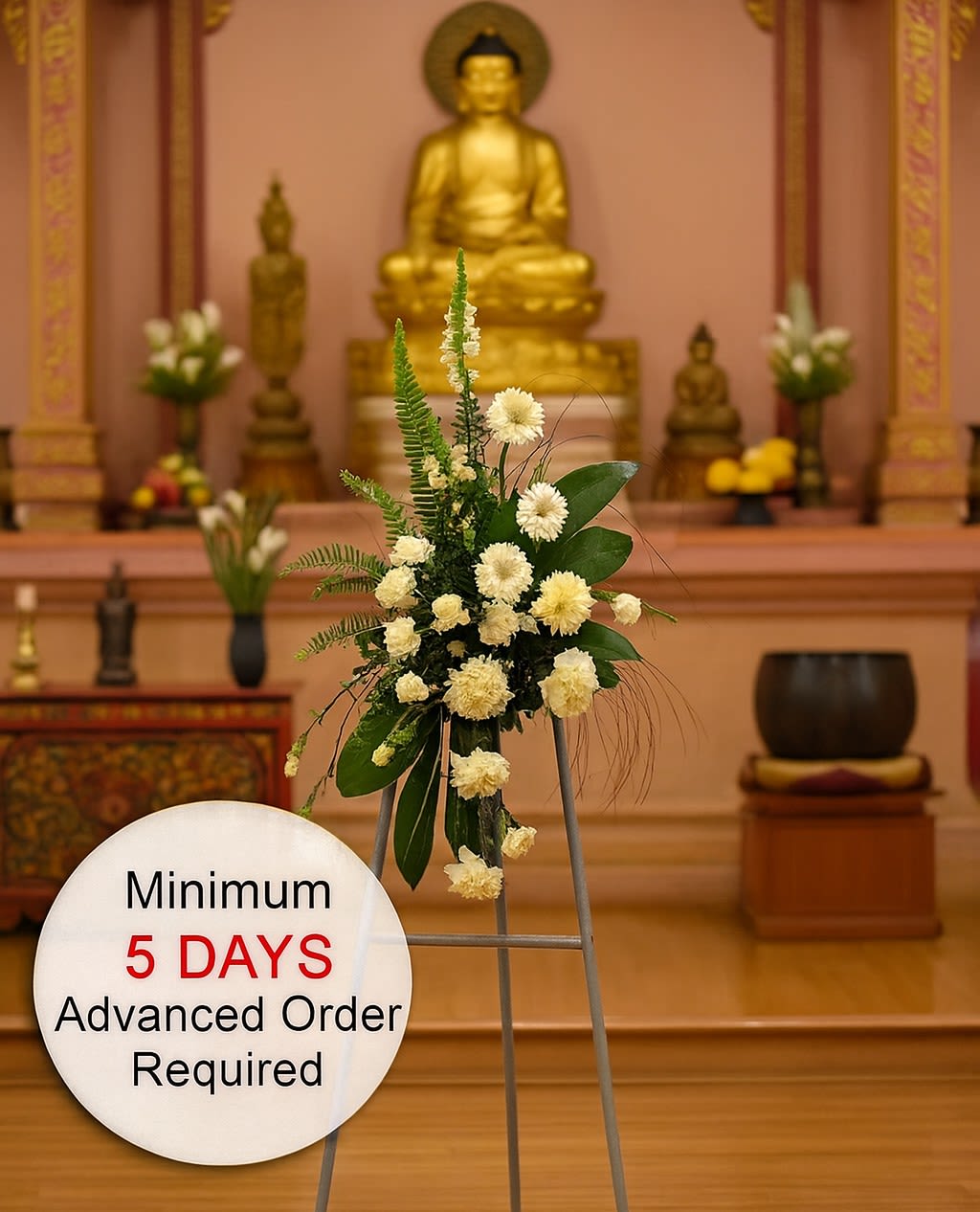 Tall white floral easel spray with greenery in a temple setting and a sign noting advance order time.