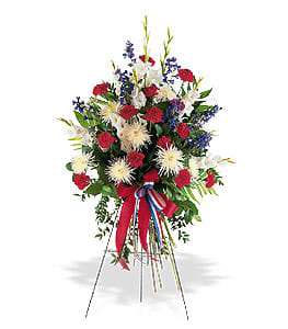 Tall red, white, and blue standing spray with carnations, mums, and ribbon on an easel