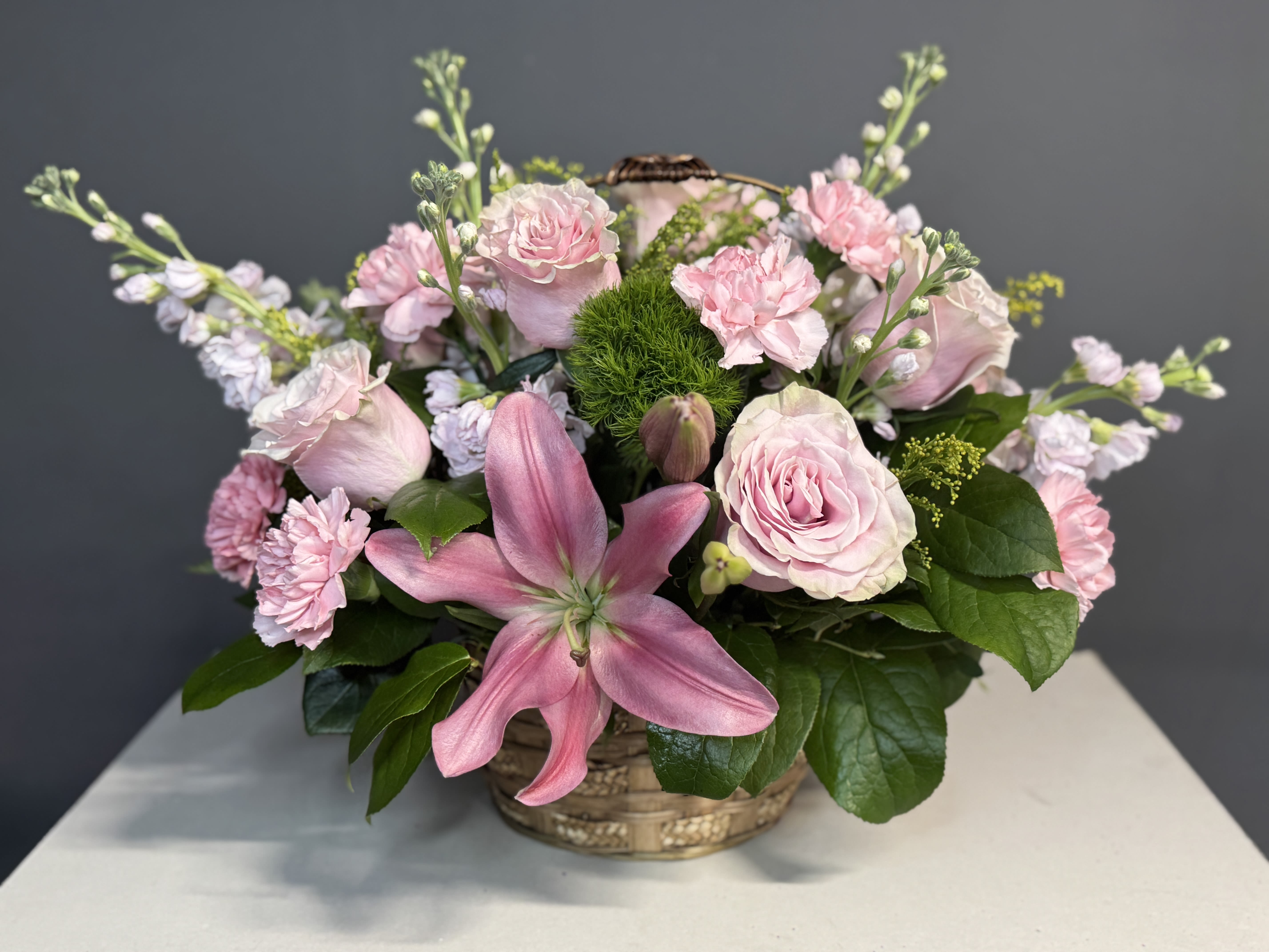 Pink roses and lilies arranged in a low basket