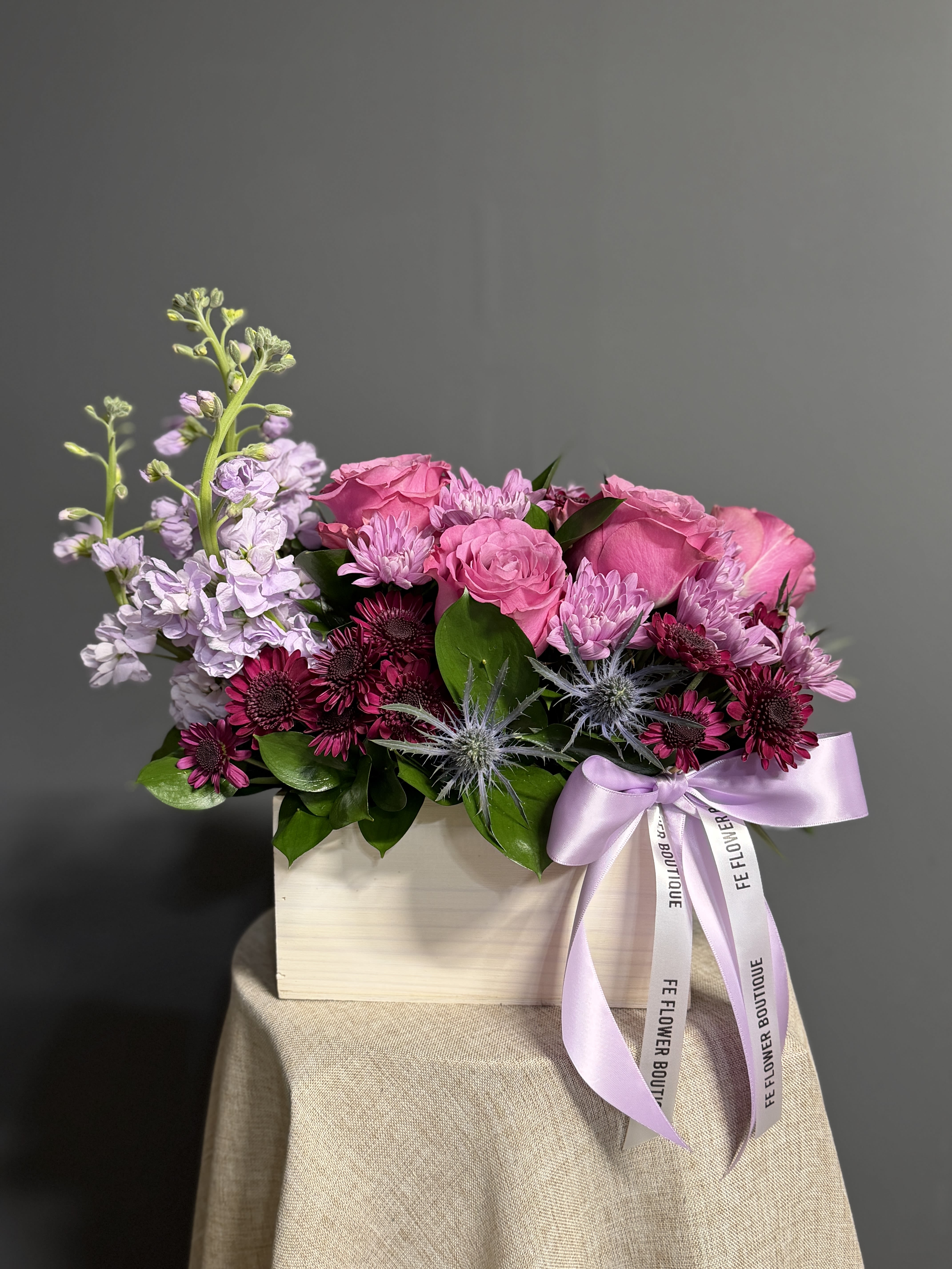 Lavender Fields - Lavender Fields is a mesmerizing floral arrangement that embodies the serene beauty of lavender. This design exudes tranquility, featuring delicate lavender roses and blooms artfully arranged in a charming white-washed box. Adorned with a soft lavender satin ribbon, this arrangement is a perfect blend of natural grace. Ideal for expressing love, calmness, and admiration, "Lavender Fields" is a thoughtful gift suitable for any occasion, promising to bring joy and serenity to its recipient.