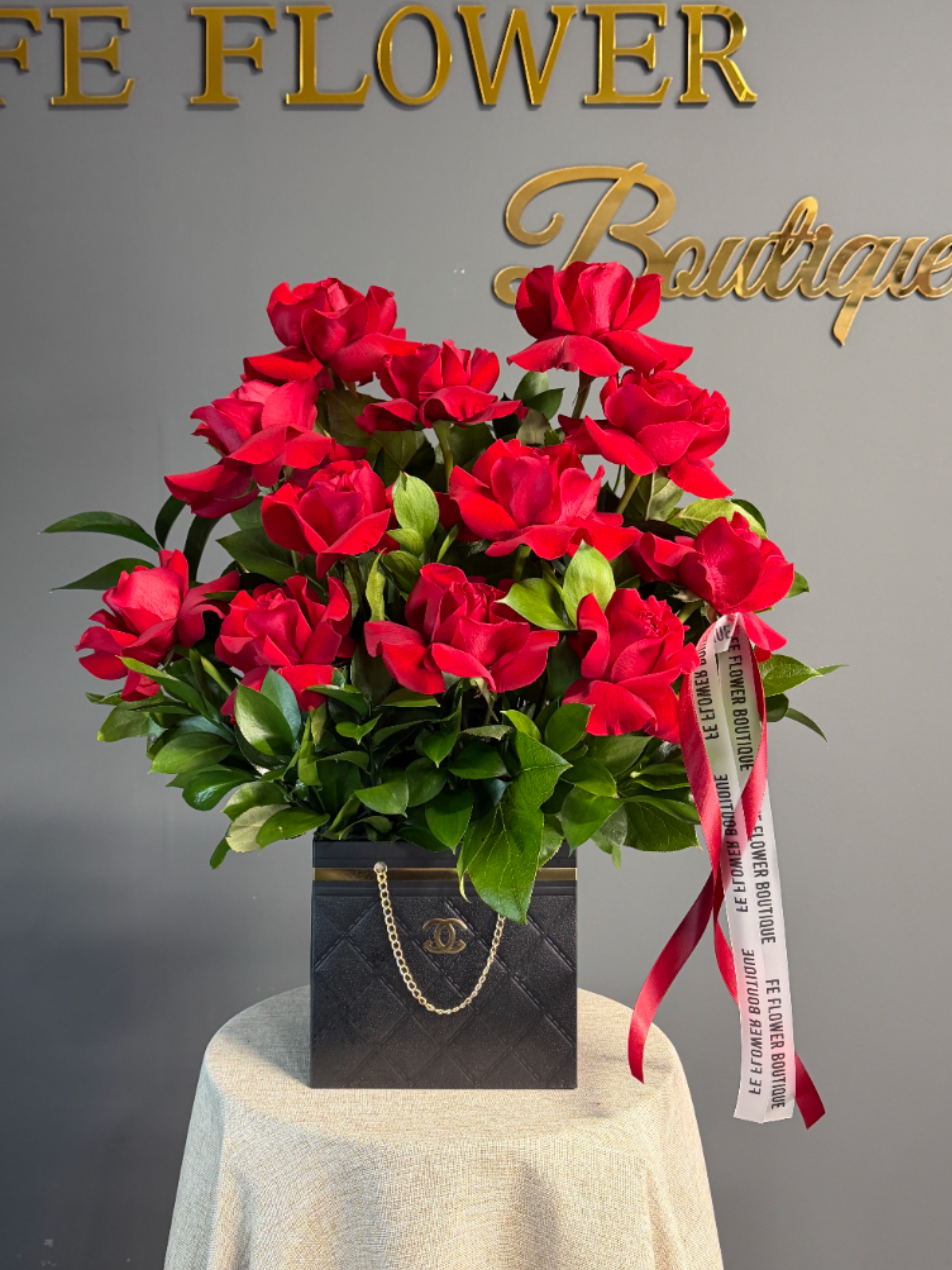 Red rose arrangement in a black box with ribbon accents