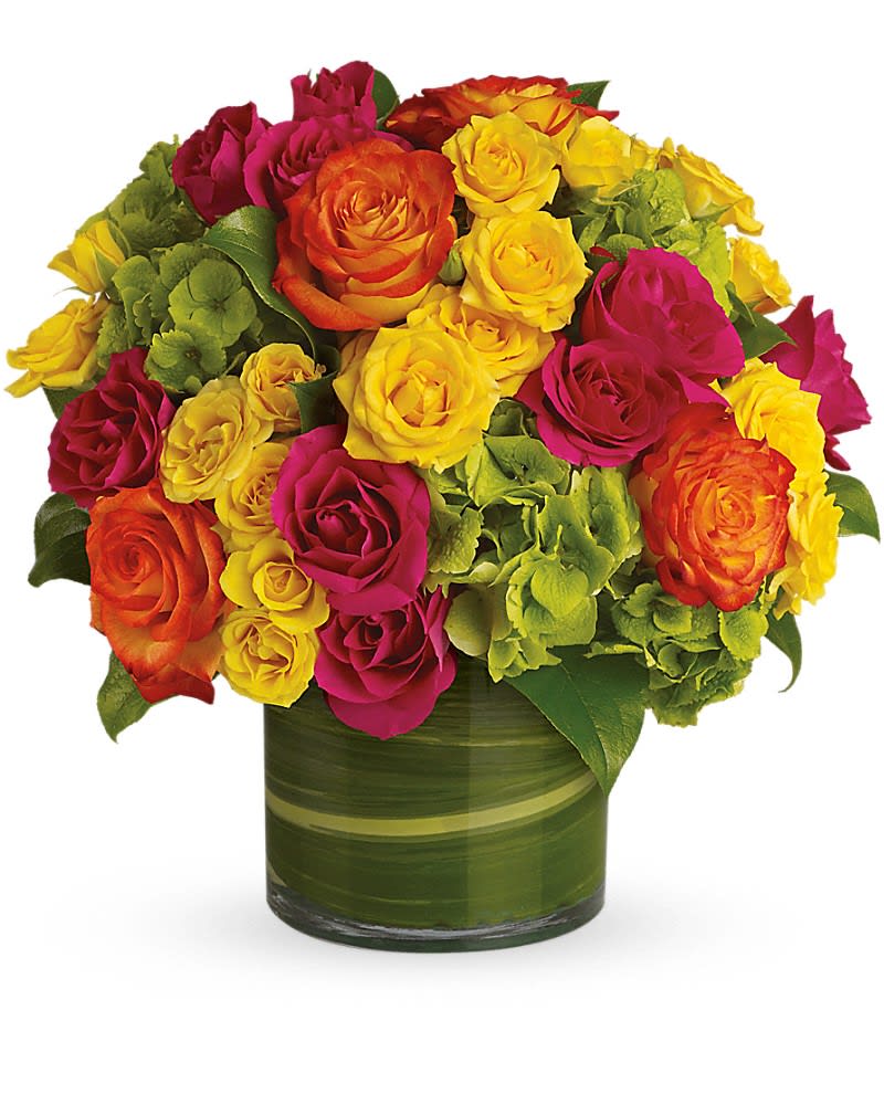 Blossoms in Vogue - Blow someone away with a bouquet that has so much style&hellip; all it needs is its own runway. Brilliant green hydrangea hot pink and bi-color roses hot pink and yellow spray roses and greens are hand-delivered in stunning style: a wide cylinder vase that's been elegantly lined with leaves. This bouquet is a singular sensation!Approximately 13" W x 12" H