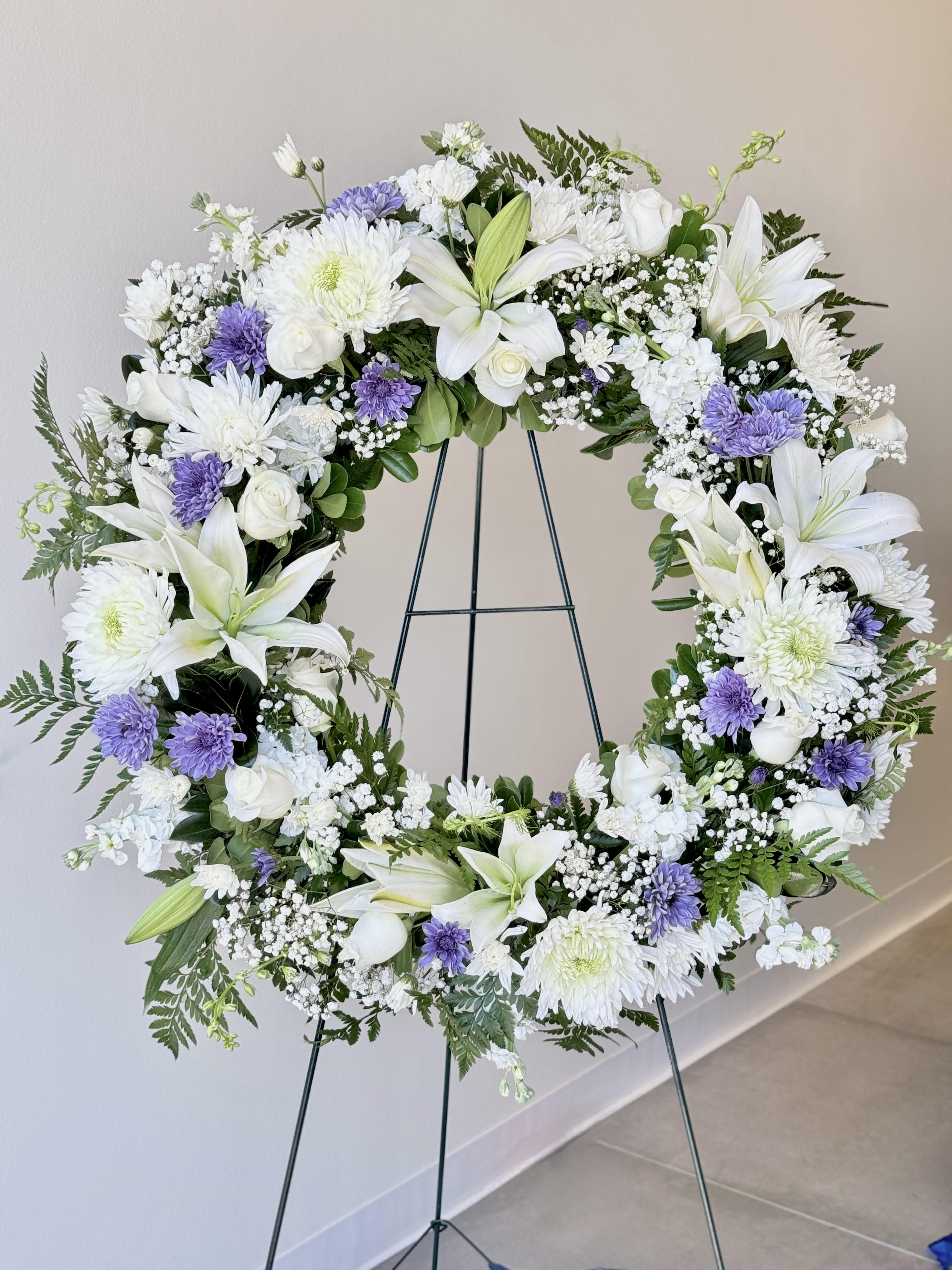 White and lavender floral wreath on a metal stand