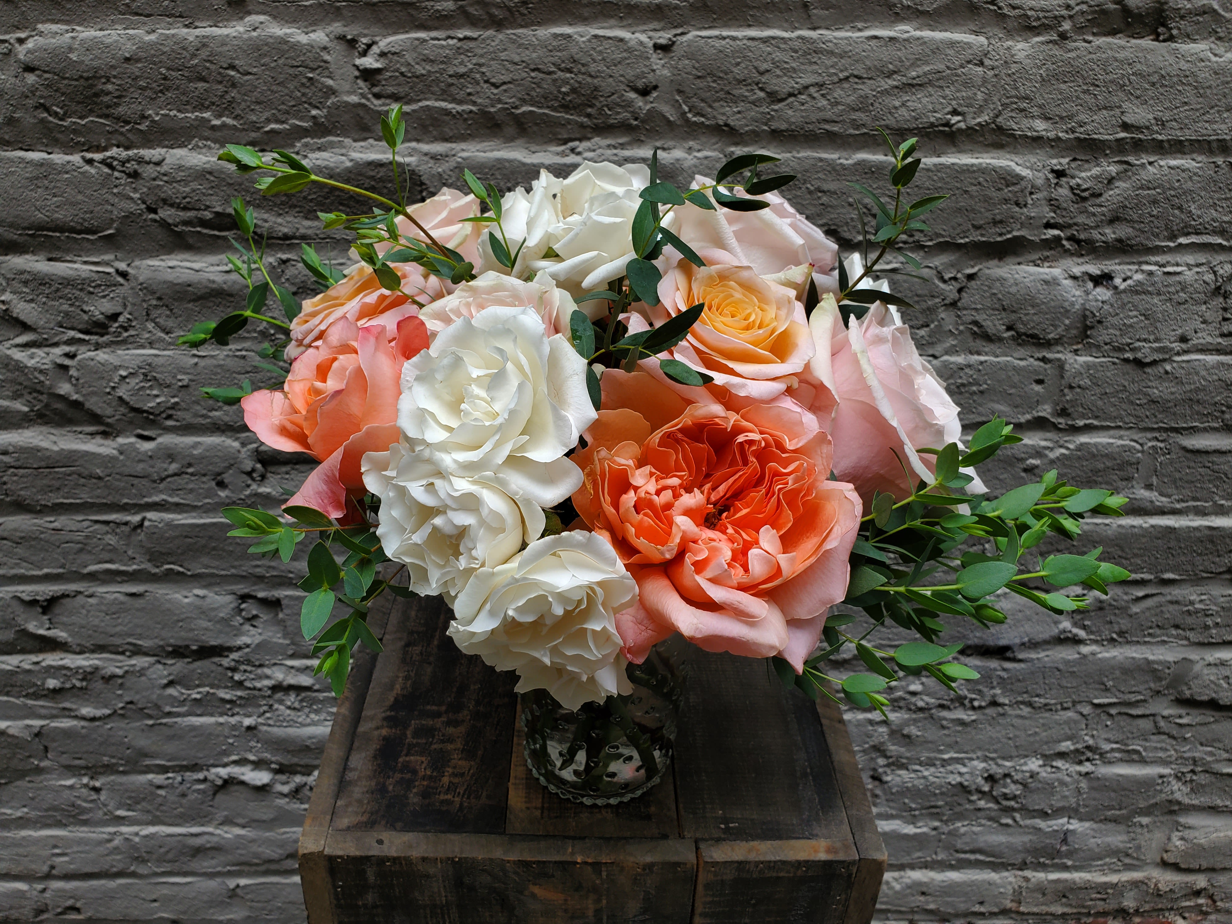 Bouquet of peach, pink, and white roses in a glass vase